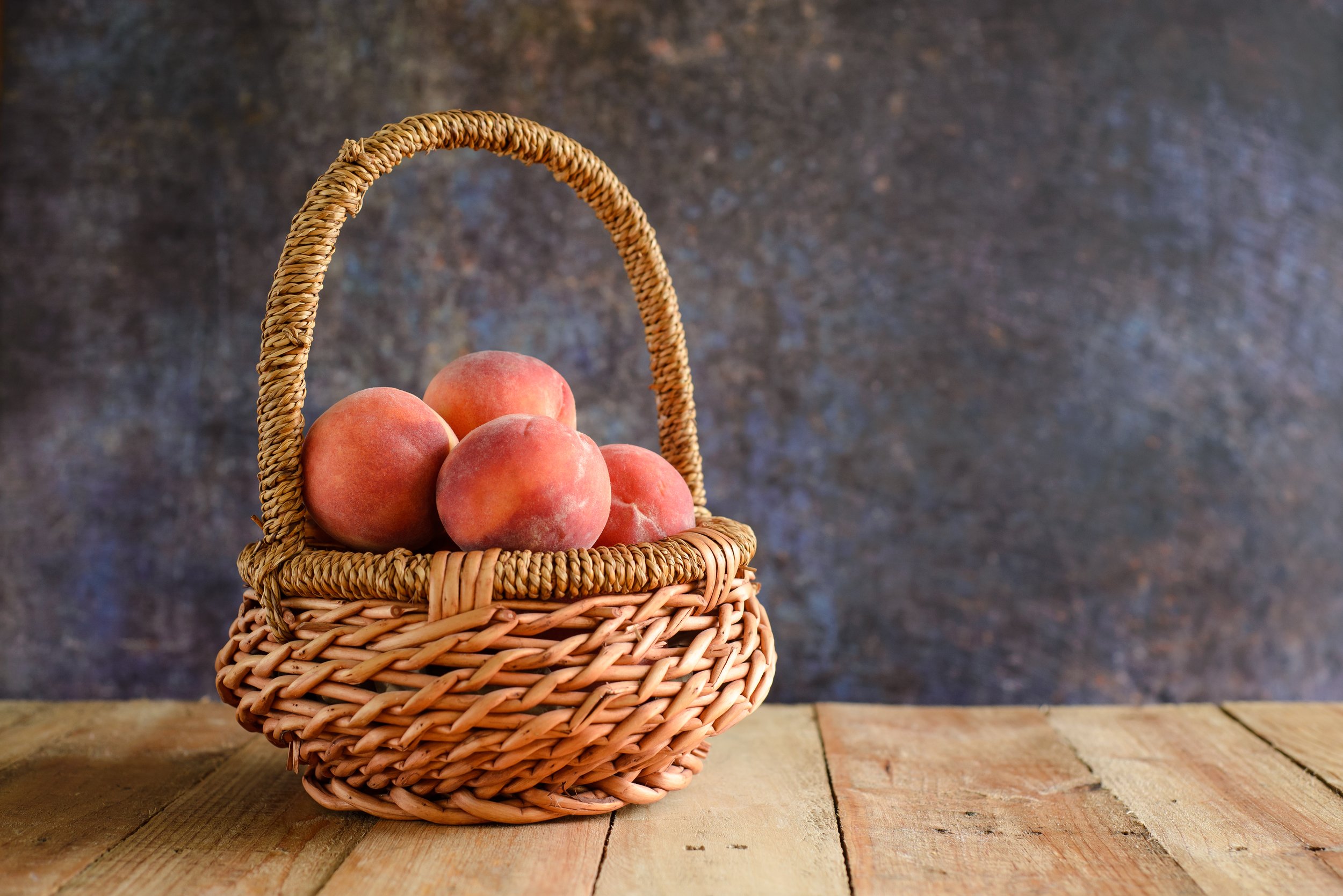 peaches-in-a-wicker-basket-on-a-wood-table-2025-03-11-16-40-55-utc.jpg