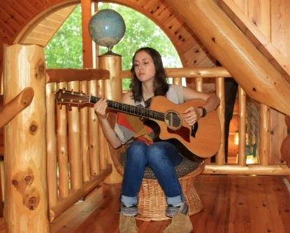 Alison Rose playing guitar at the log cabin