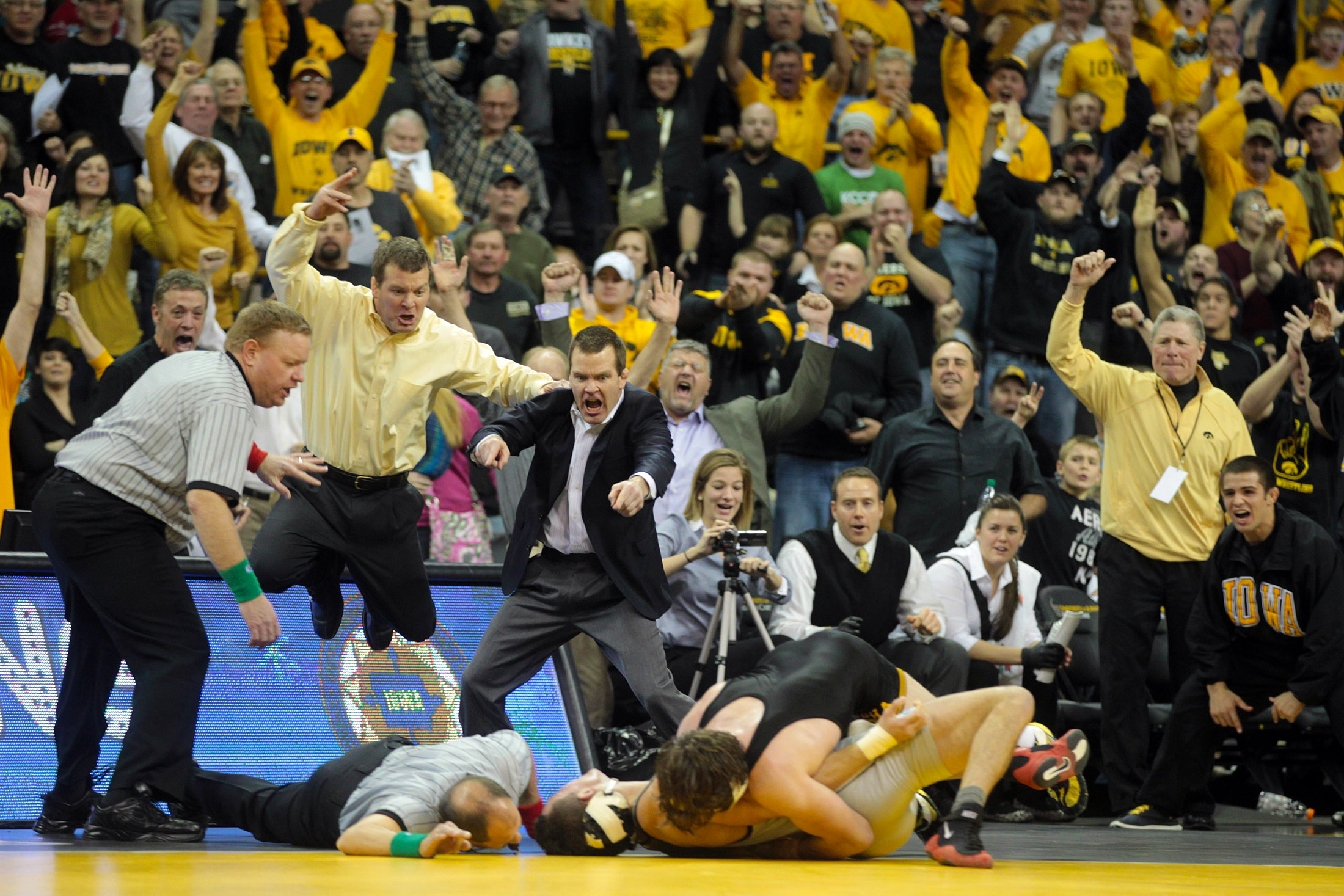  Iowa head coach Tom Brands, left, and associate head coach Terry Brands, second from left, leap in the air as Mike Evans throws down Ohio State's Nick Heflin for a 9-4 overtime win. 