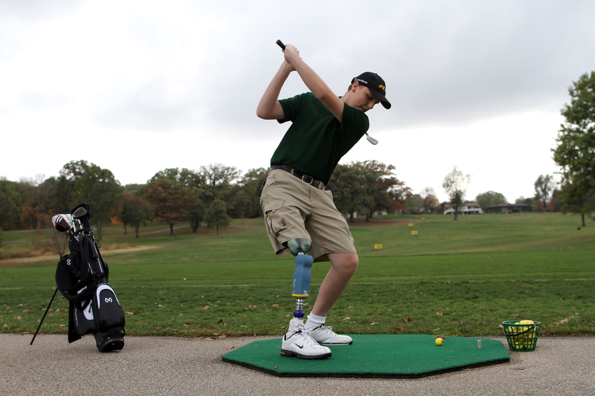 Drew Wall practices at the Ellis Golf Course driving range. Wall's prosthetic leg has a customized torquing mechanism at the ankle to allow Wall to fully twist while swinging his club.