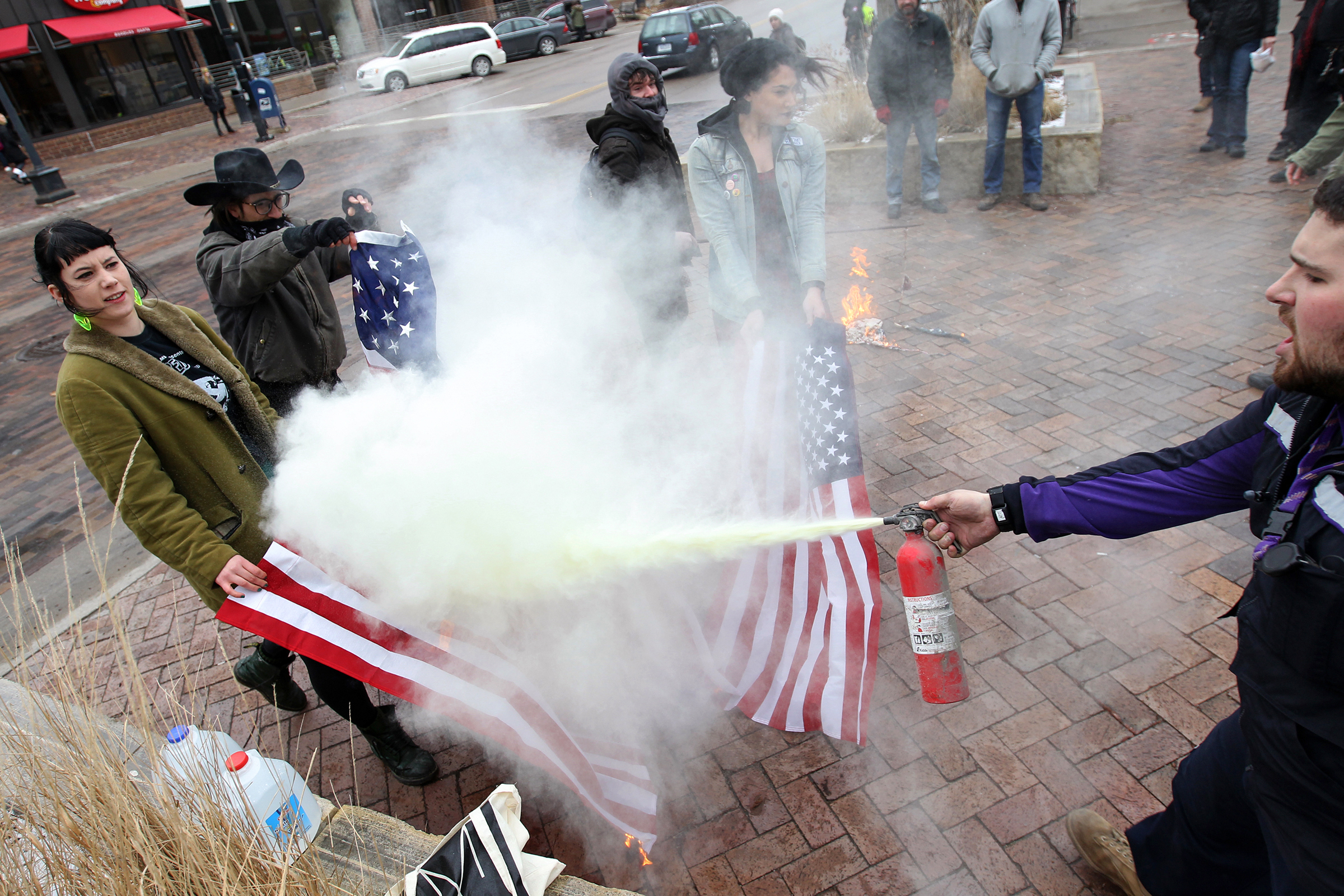 FedEx employee Matt Uhrin extinguishes a set of American flags being set on fire by protesters.