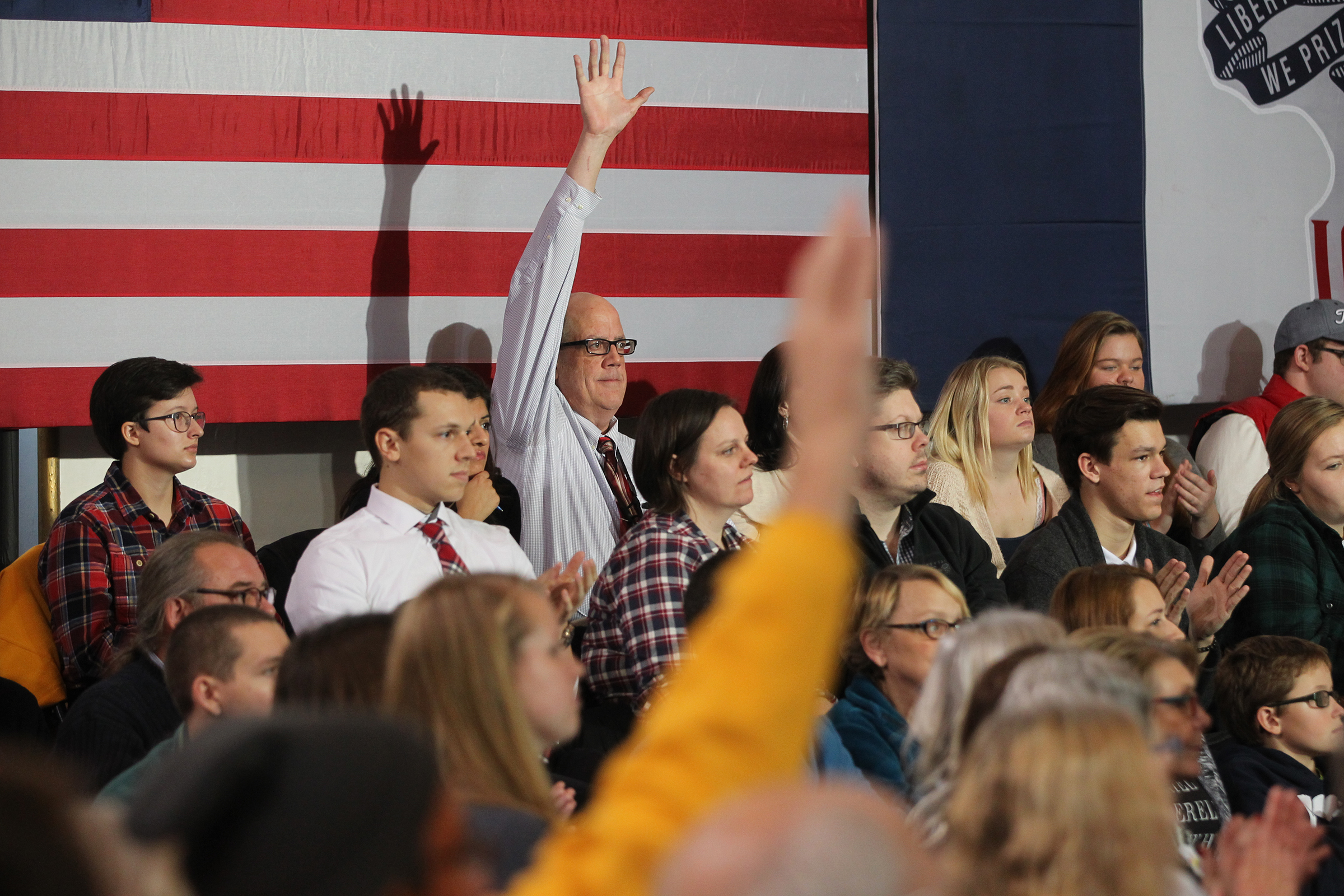 A man raises his hand as Democratic presidential candidate Hillary Clinton looks for questions at Old Brick Church.