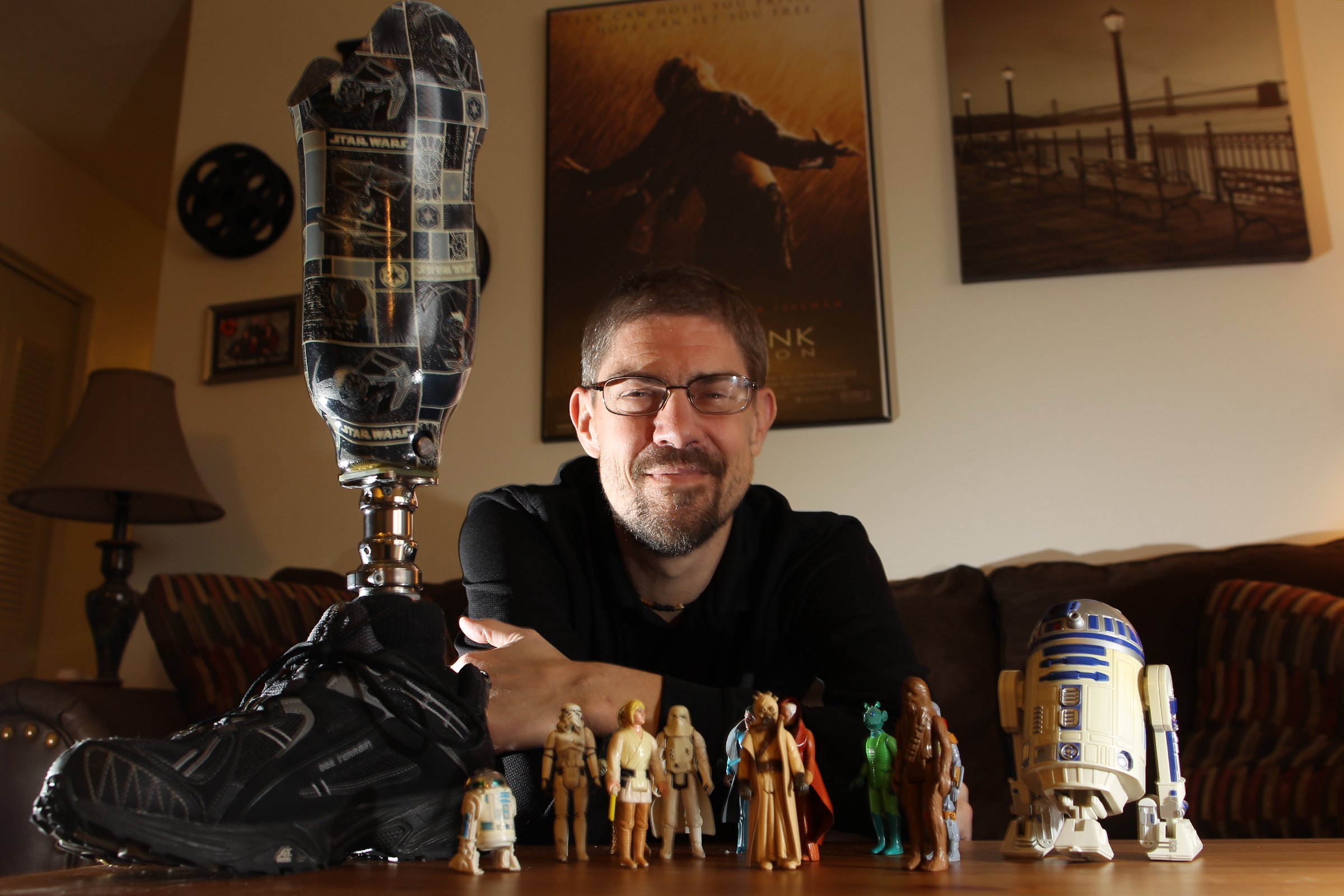 Brian Kleis poses with his Star Wars-themed prosthetic leg and original Star Wars memorabilia at his home.