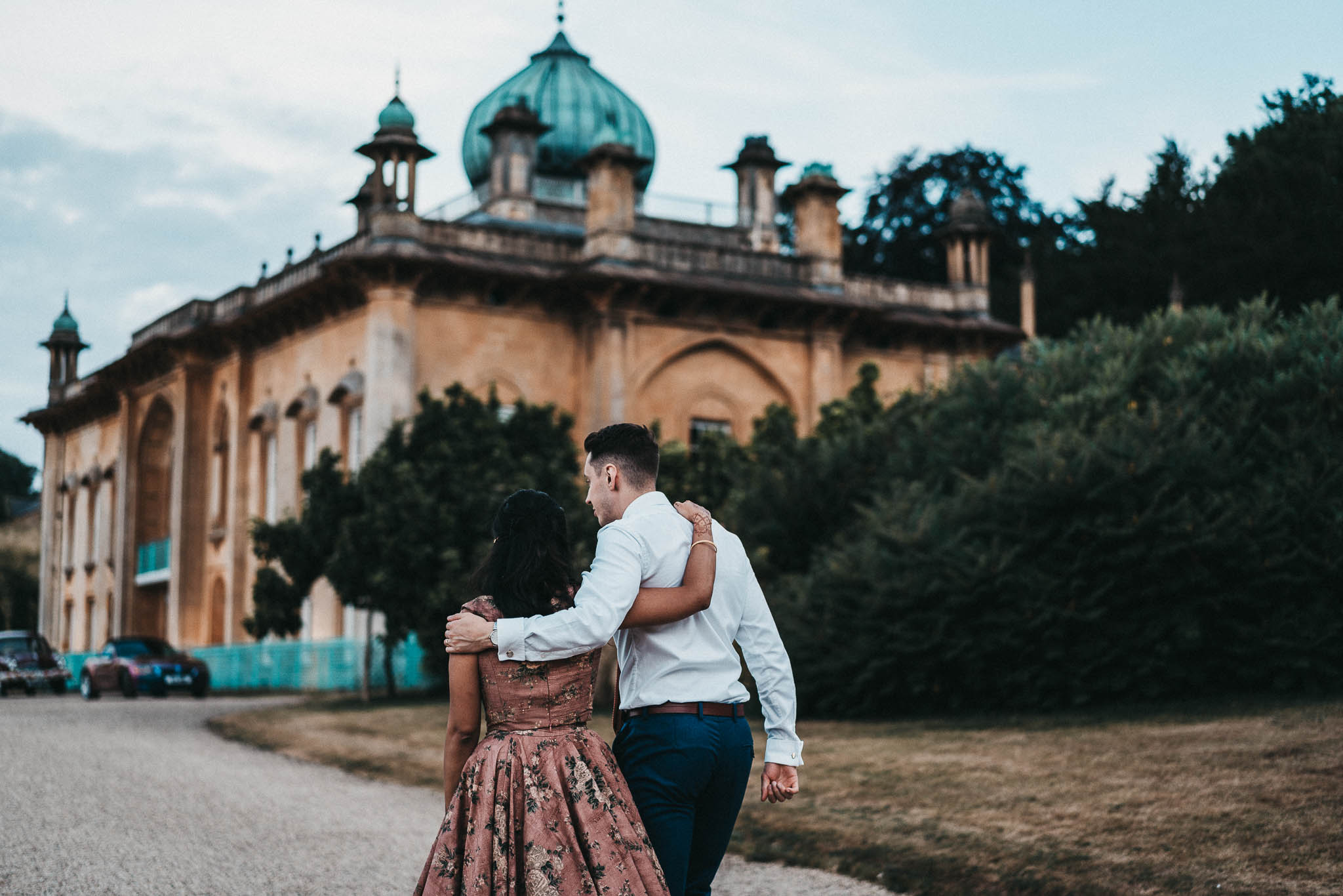 bride and groom walking with arms round each other past sezincote house in the cotswolds