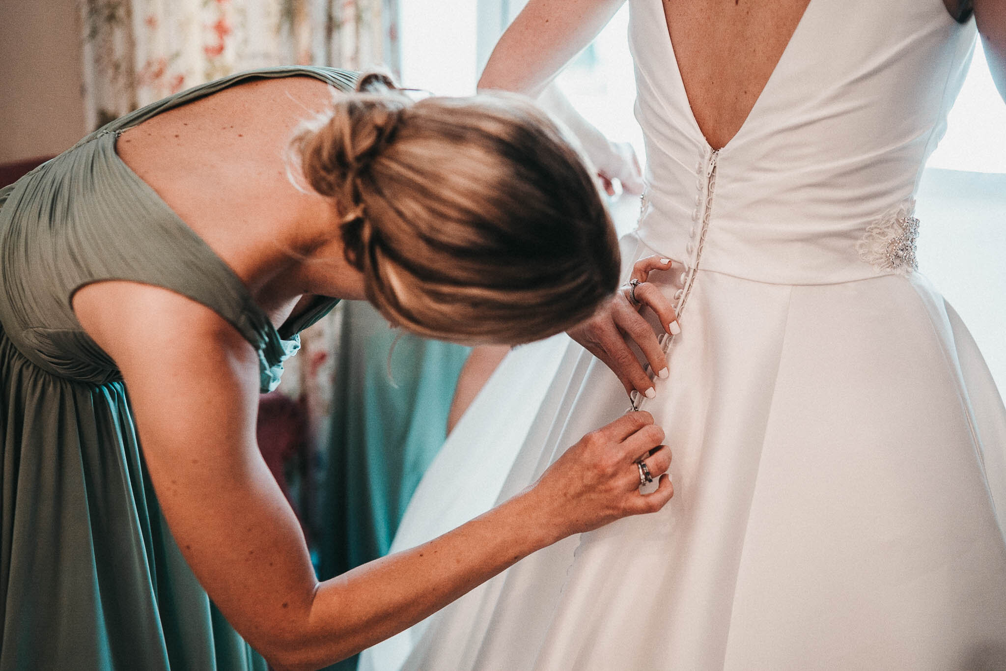 bride-having-dress-adjusted-by-bridesmaid