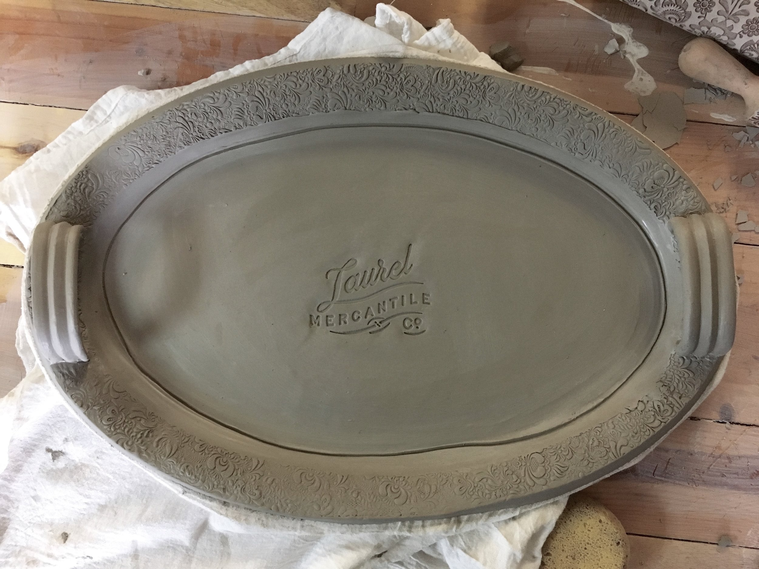 Handled Laurel Mercantile Co. platter in wet clay. 