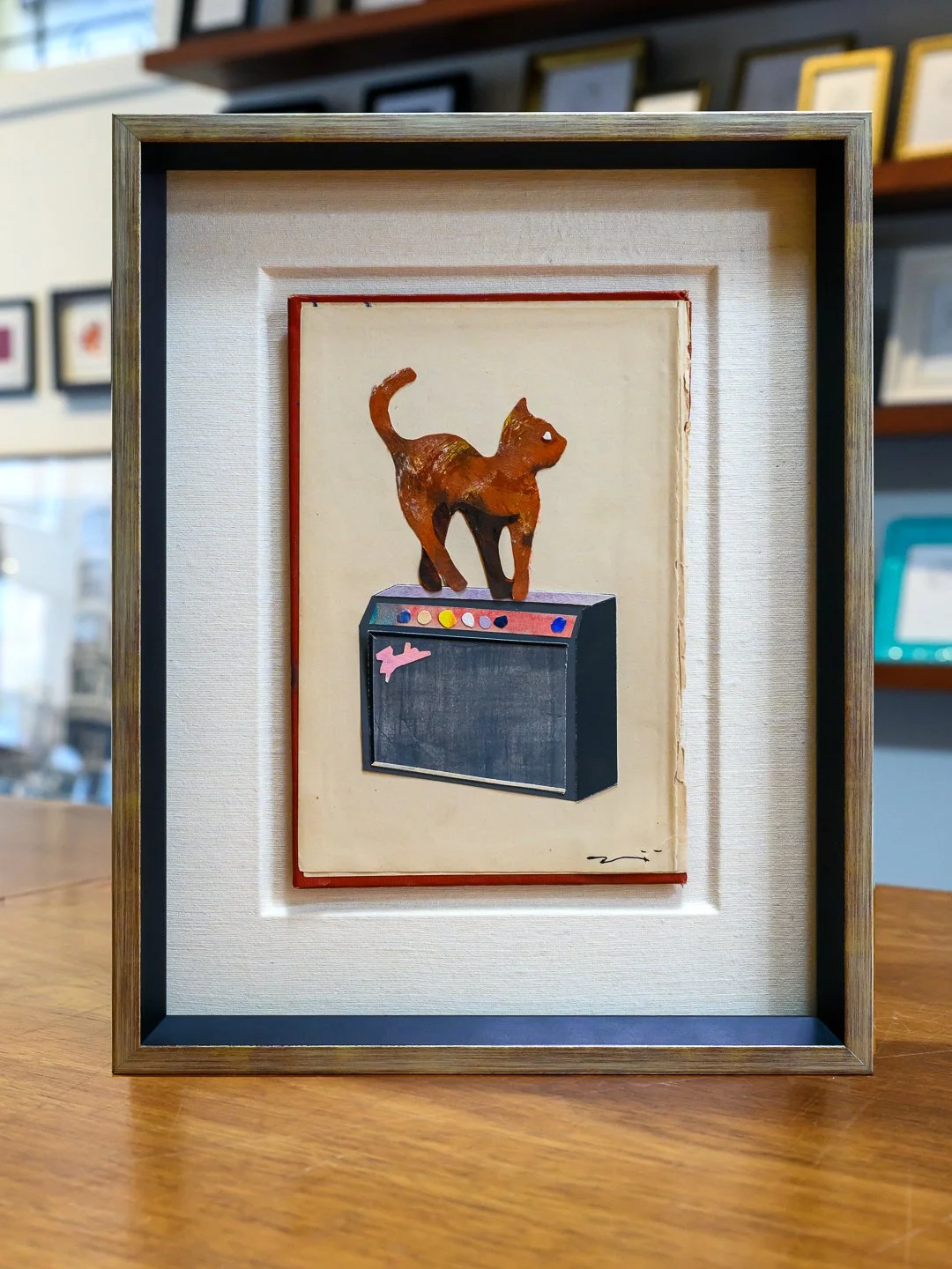 Tadahiro Gunji collage of a cat on an amplifier floated and recessed into a fabric mat with brushed silver frame and museum glass at a San Francisco custom frame shop