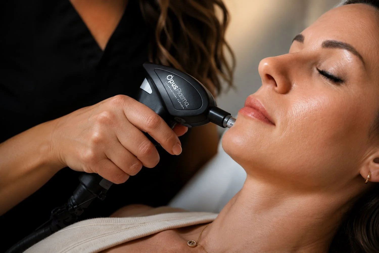 Gloved hand guiding an Opus Plasma handpiece along a client's jawline during skin resurfacing