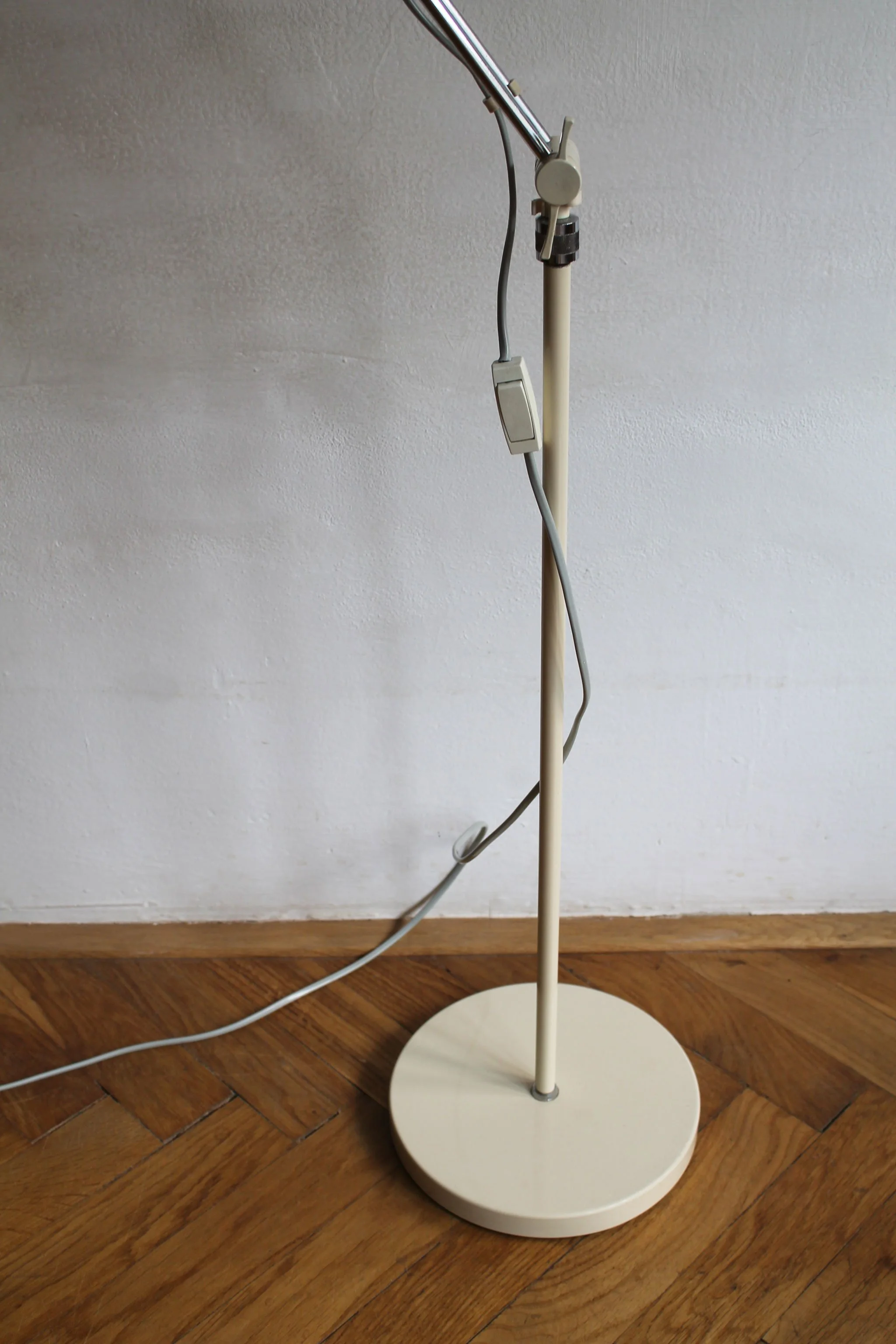 Base view of freestanding beige metal lamp on parquet floor