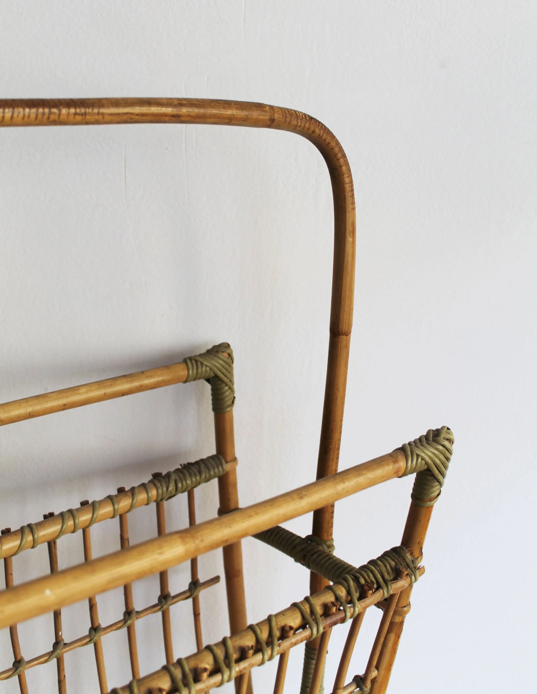Detail of hand-wrapped olive-green bindings and bent cane joints on vintage Czechoslovak magazine rack