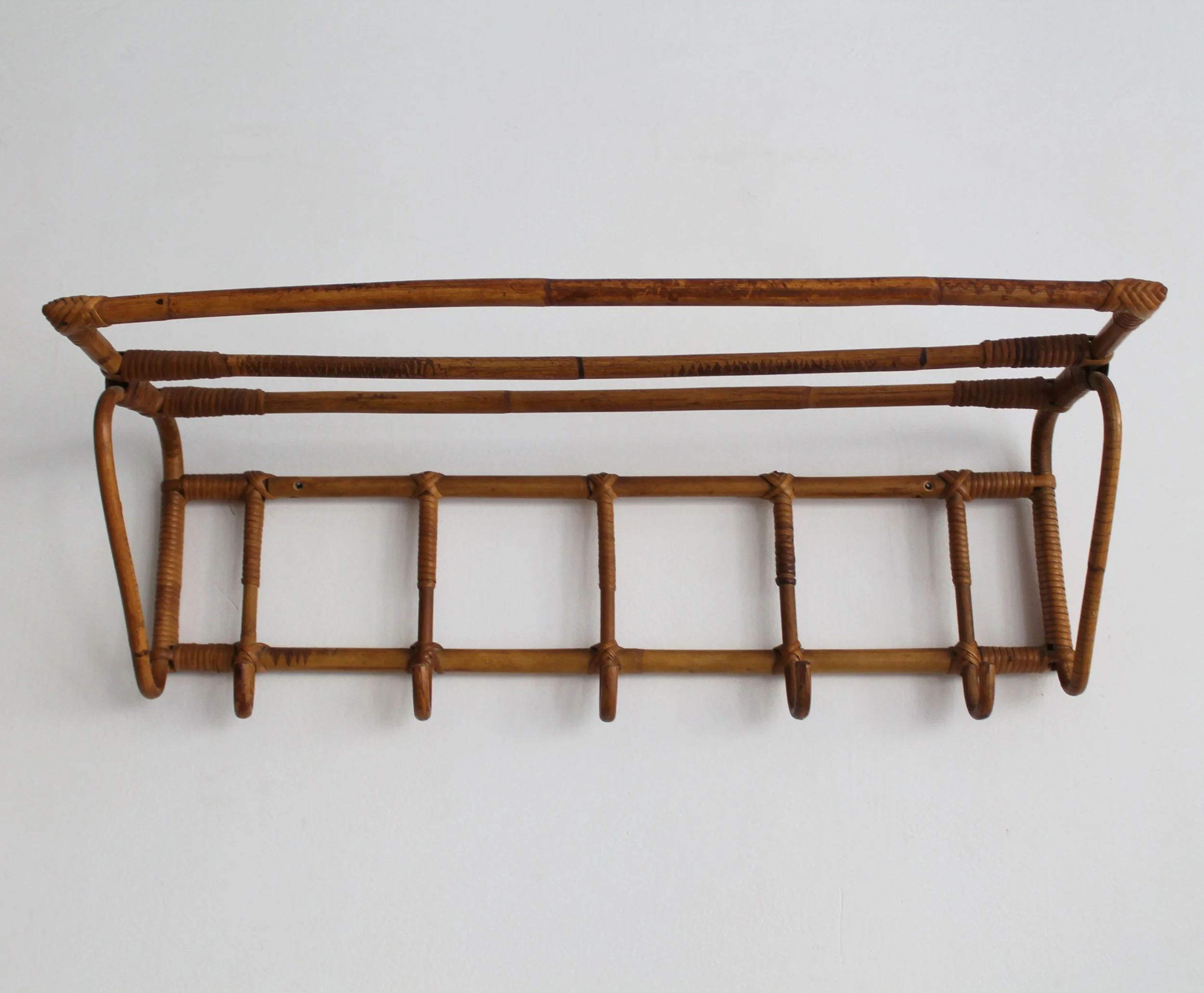 Angled view of 1960s ÚLUV attributed rattan wall coat rack with five hooks and upper shelf.jpg