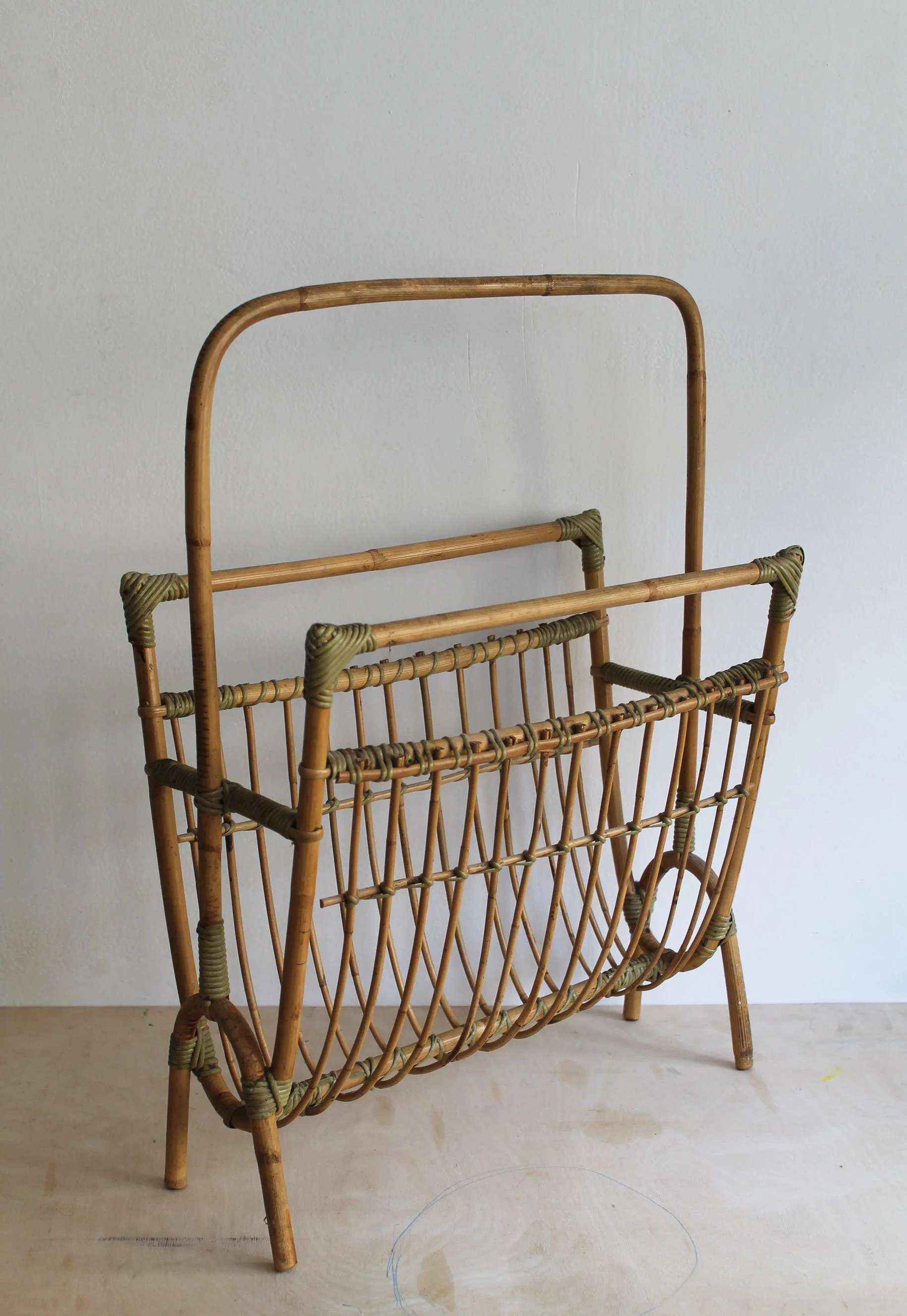Side view of sculptural 1960s Czechoslovak rattan magazine rack with curved cane frame and tall handle