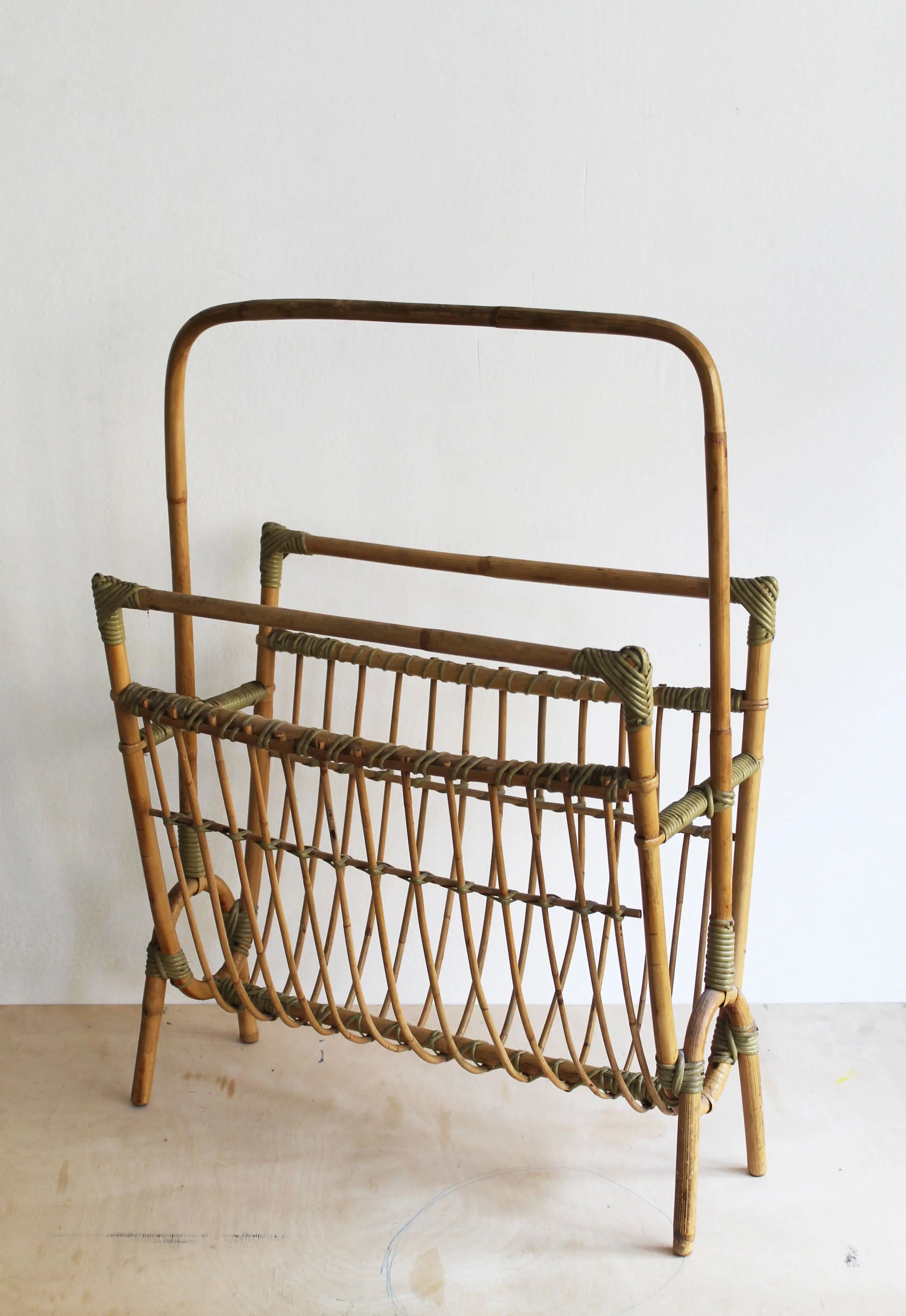 Top view of vintage rattan magazine rack showing curved cane supports, circular end detail and wrapped joints