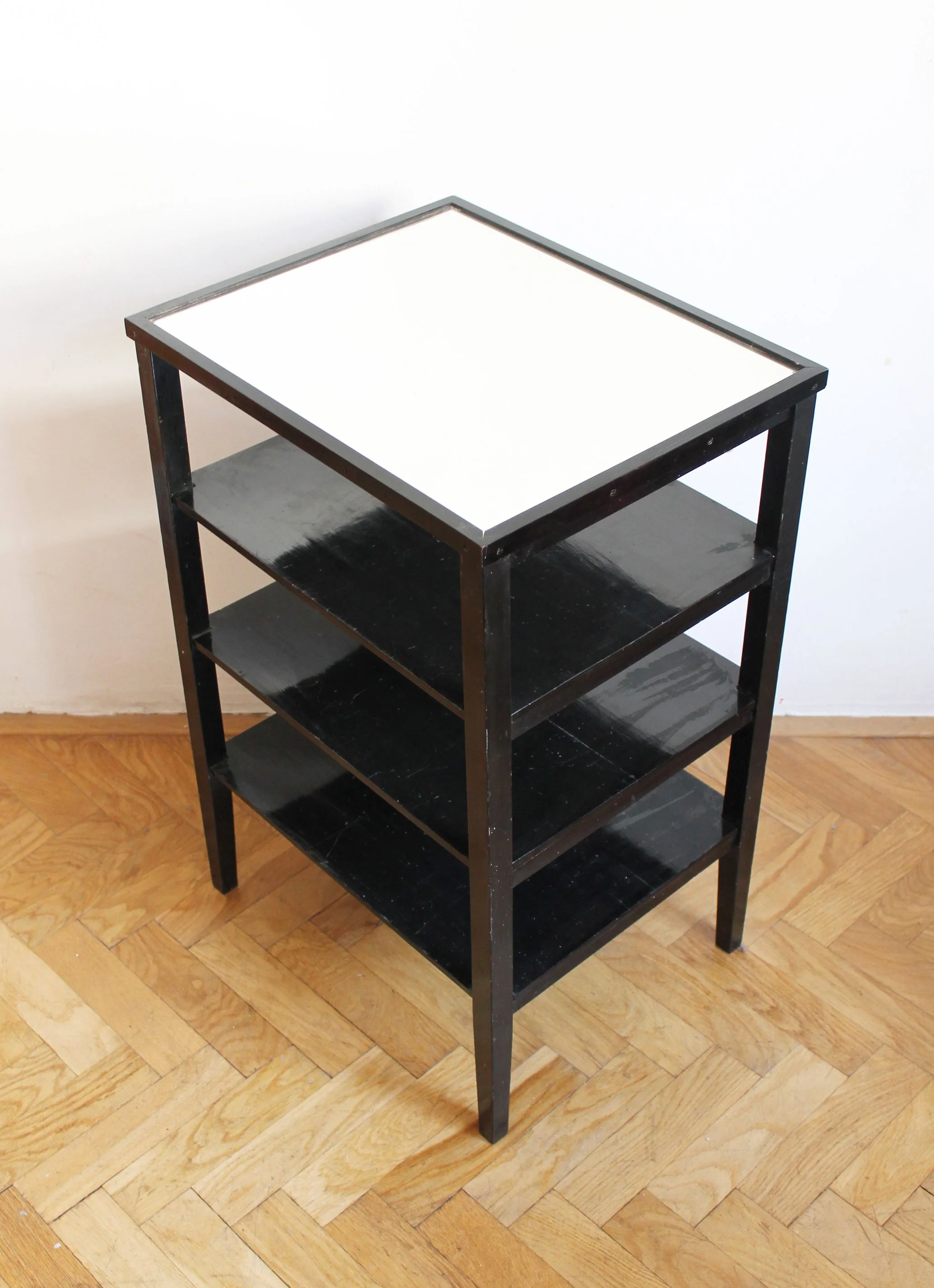 Rear three-quarter view of a black Czechoslovak Modernist étagère with three open shelves.jpg