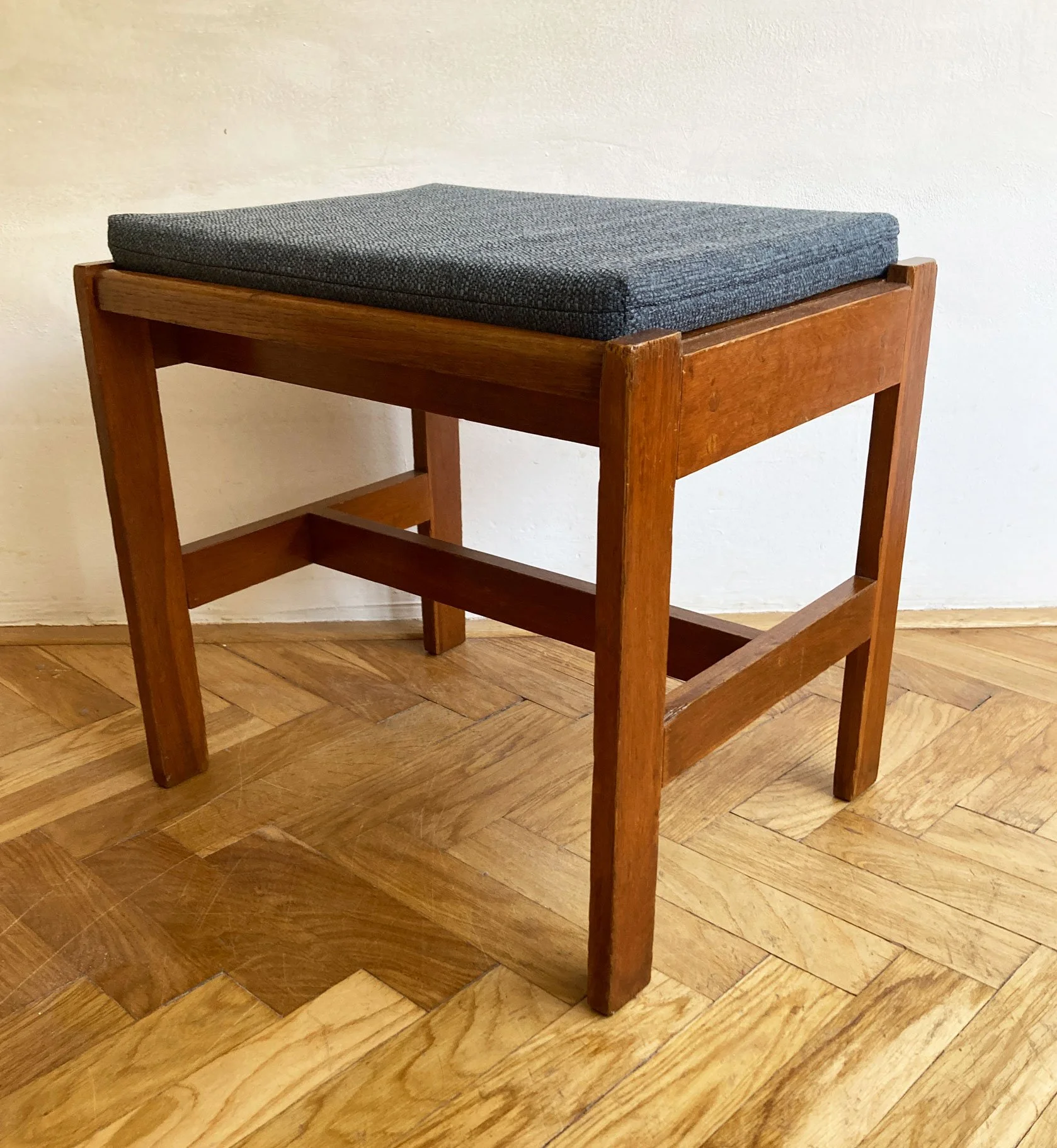 Minimalist cubic wooden stool with fabric cushion, mid-century design.jpg