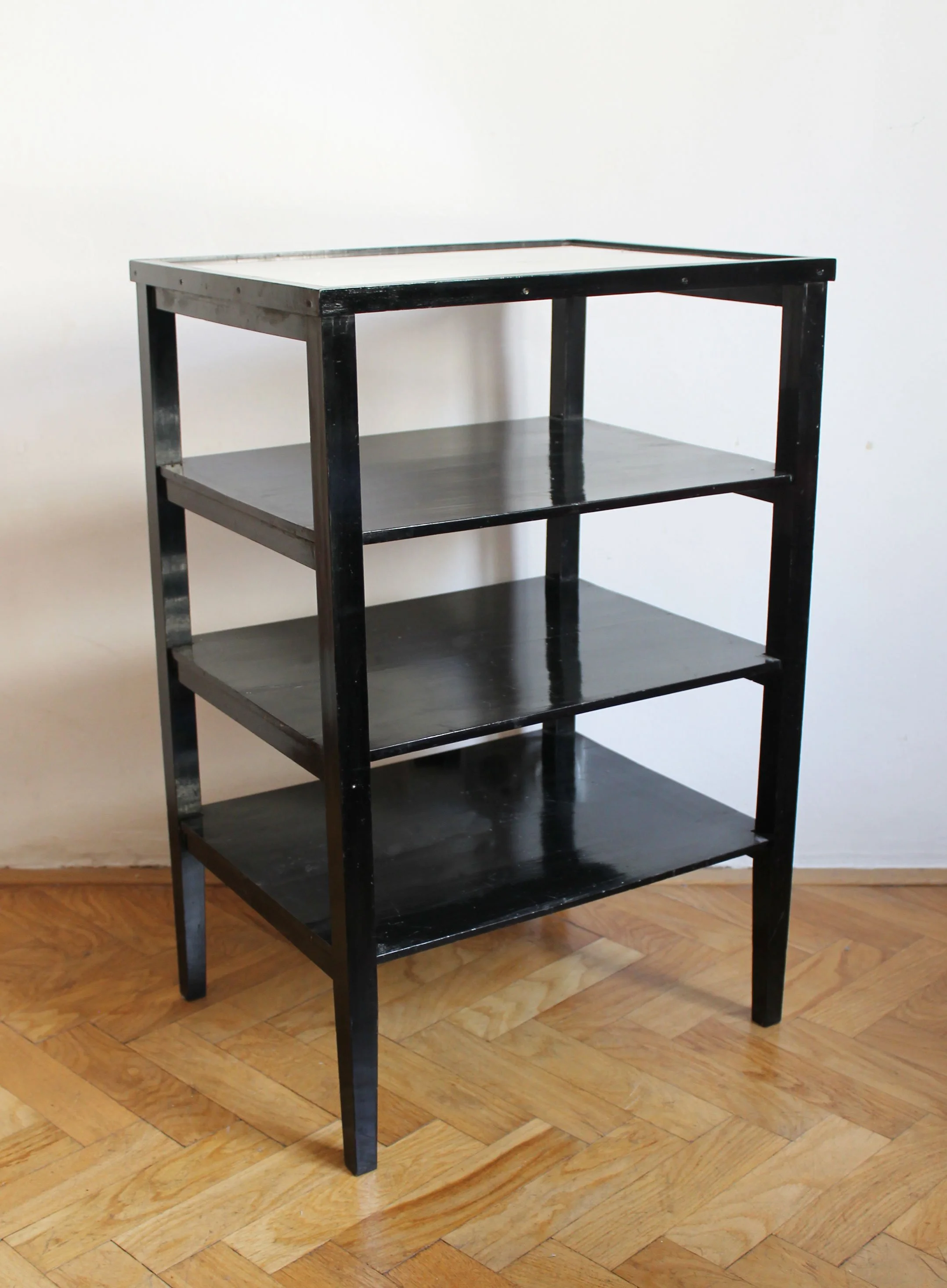 Late 1940s black Functionalist display table showing slender square legs and open shelf construction.jpg