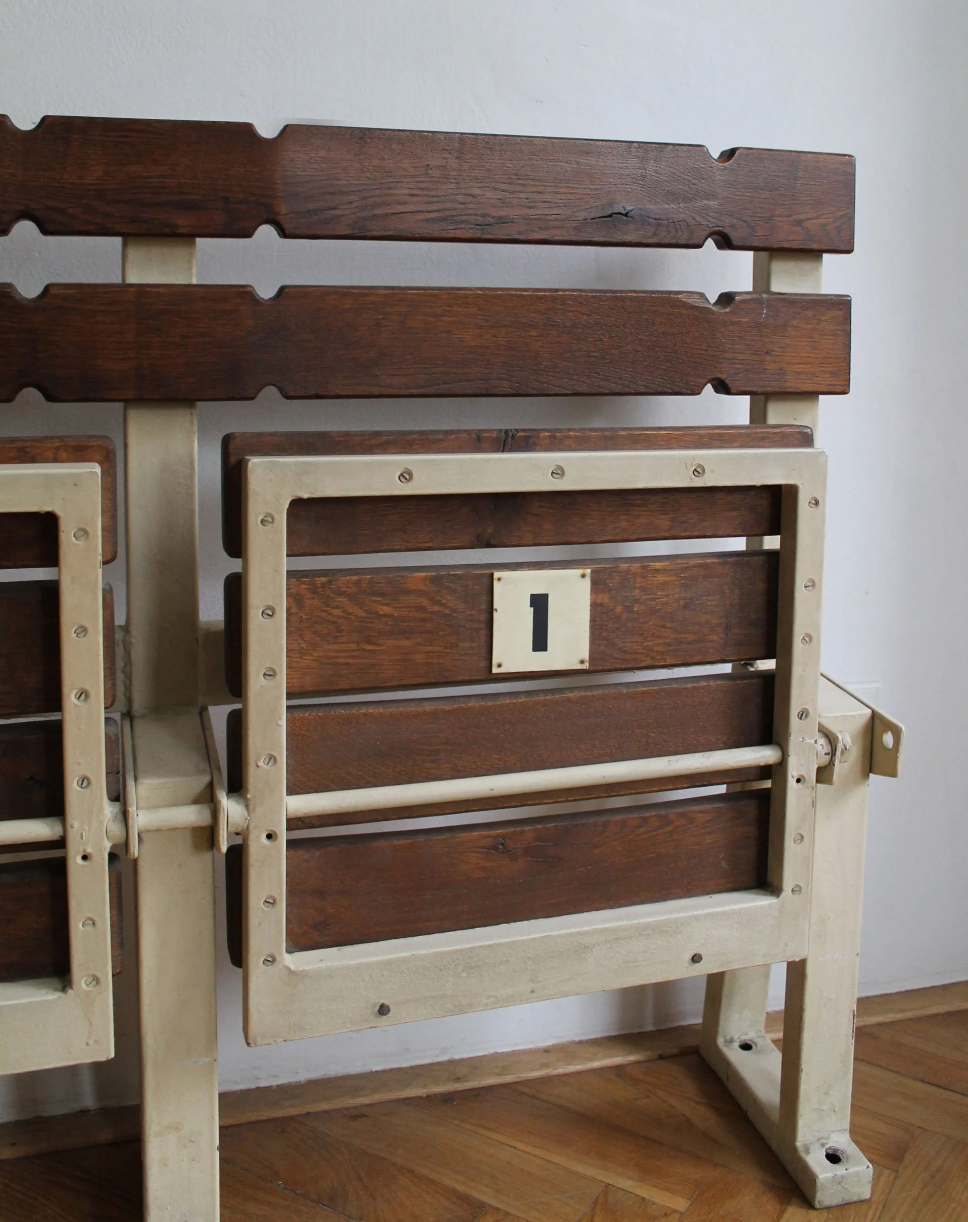 Cream-painted steel frame and dark-stained beech seating of 1970s Vodova stadium bench