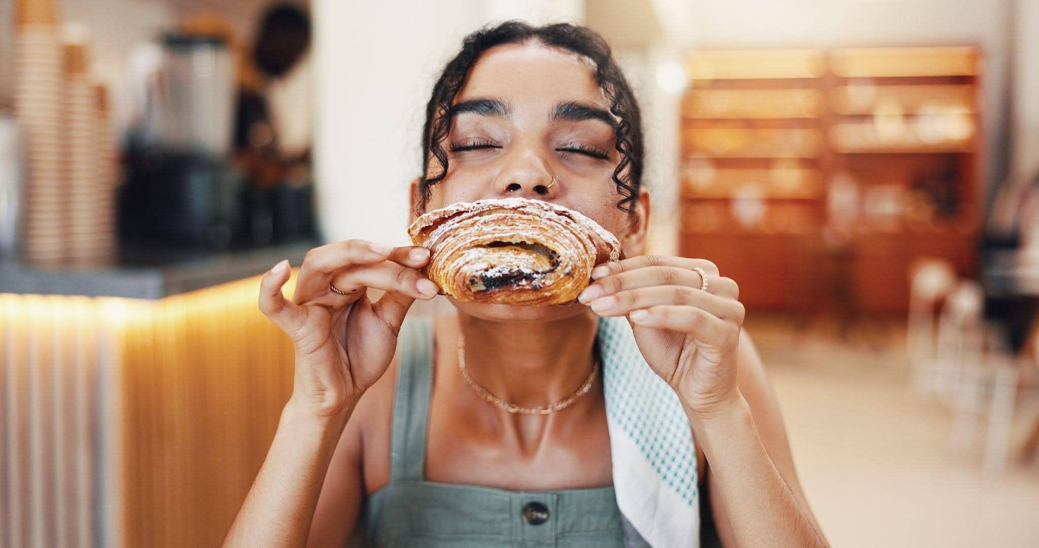 a happy woman eating a pastry