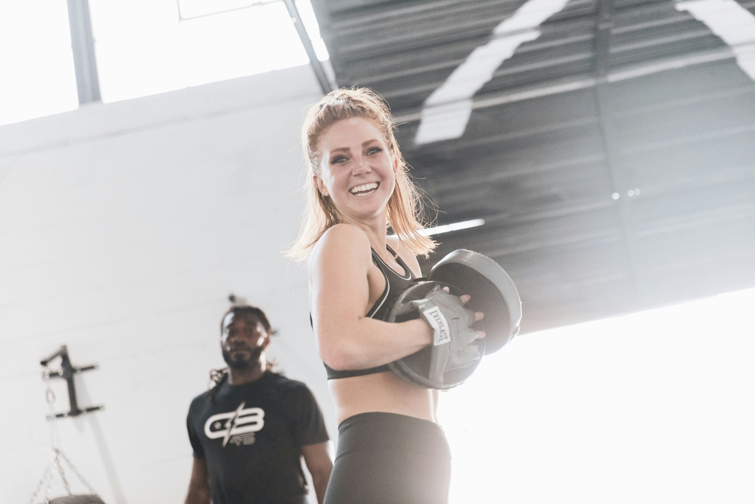 a woman smiling and boxing in the gym