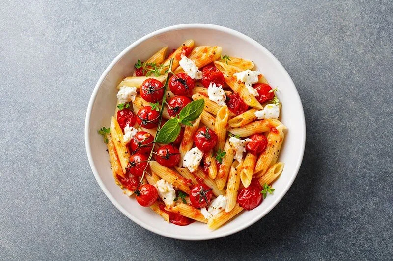 a bowl of pasta with roasted tomatoes and mozzarella