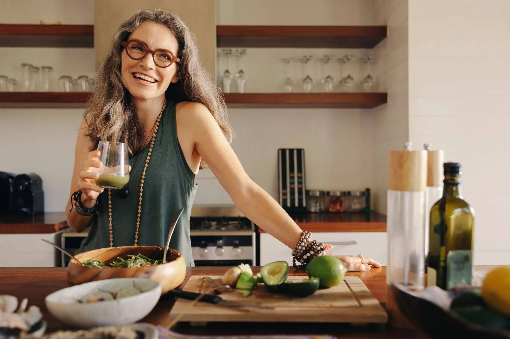 a senior woman drinking juice and preparing salad