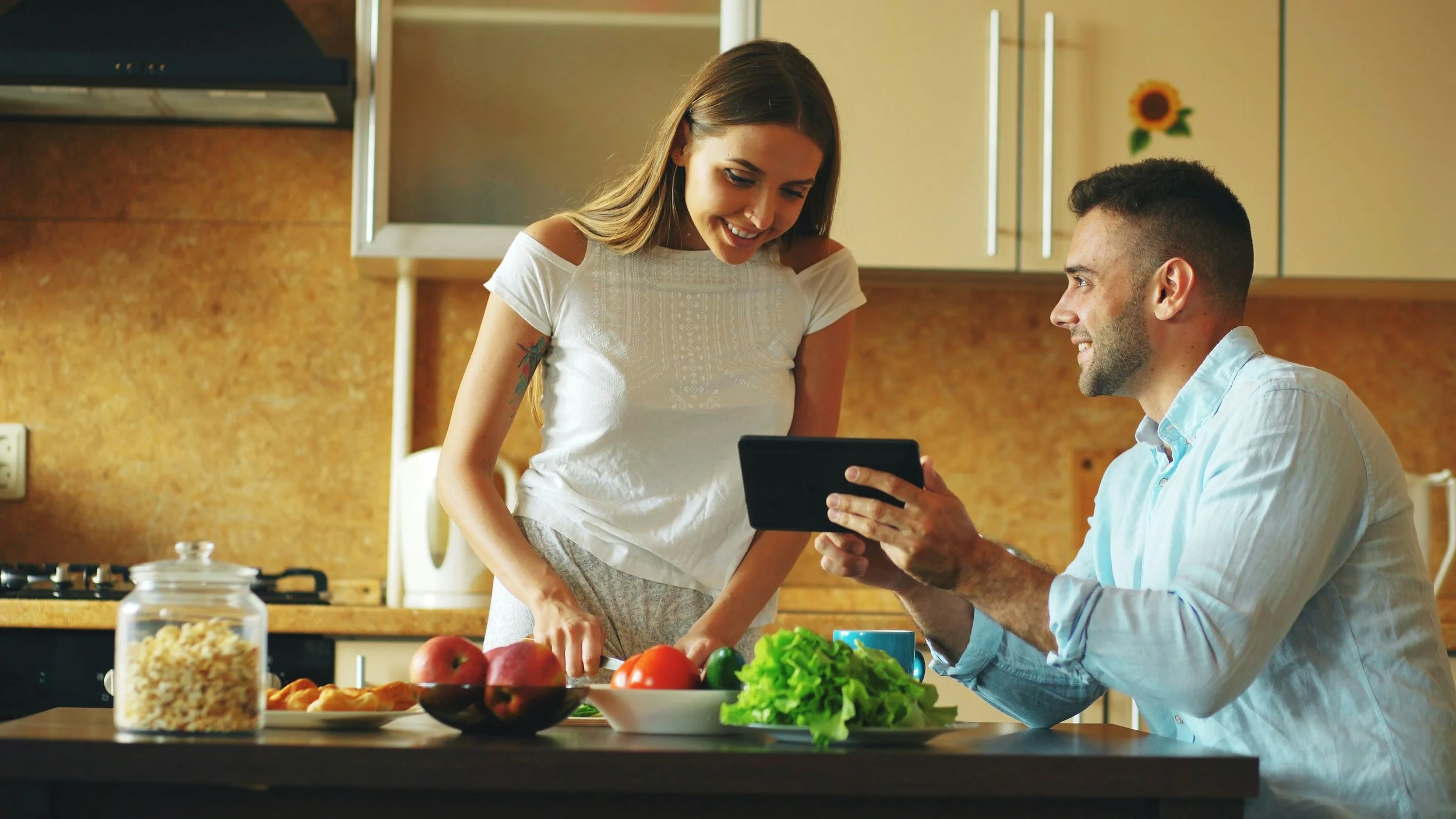 a man showing his phone screen to a woman in the kitchen