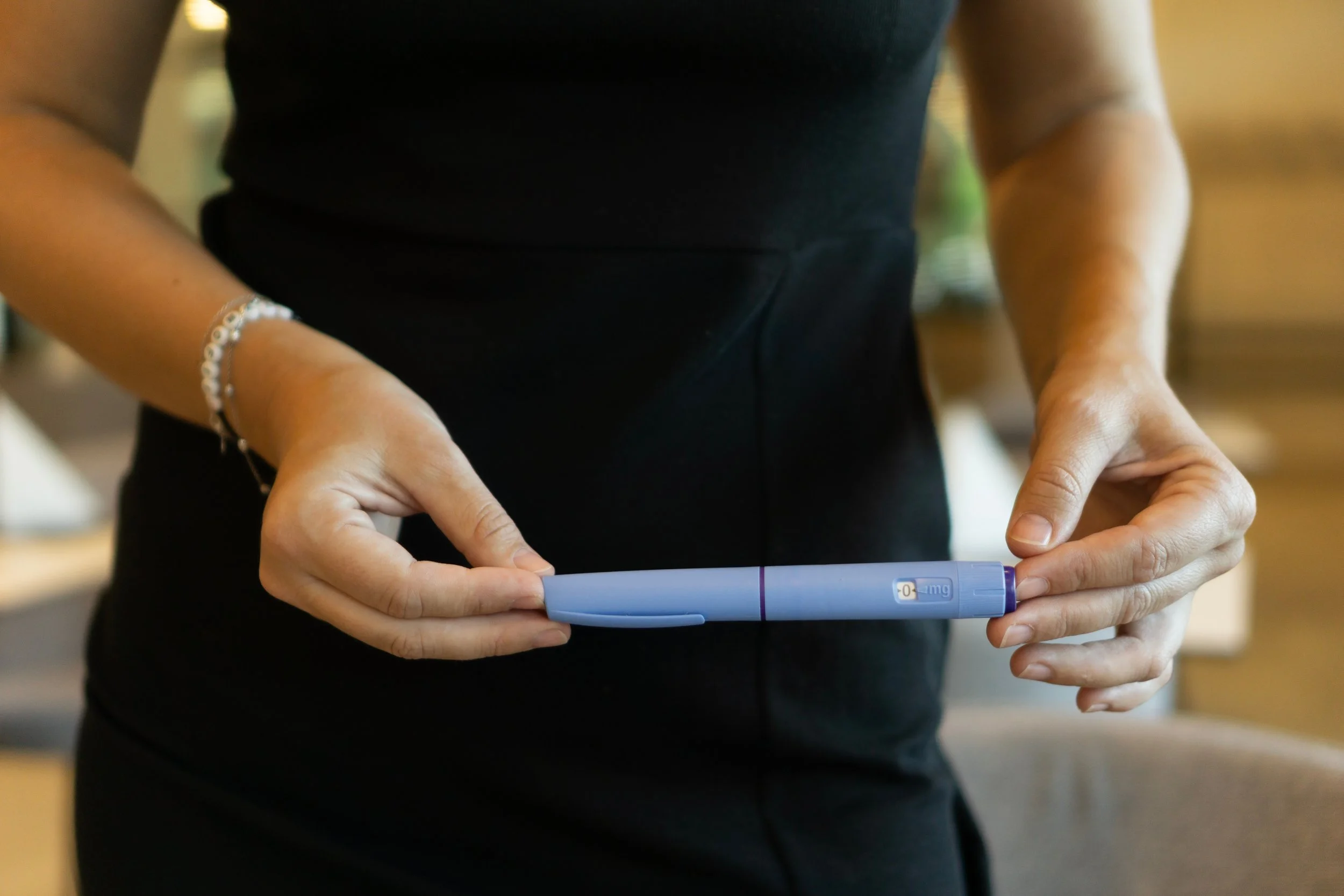 a woman in a black dress holding an Ozempic pen