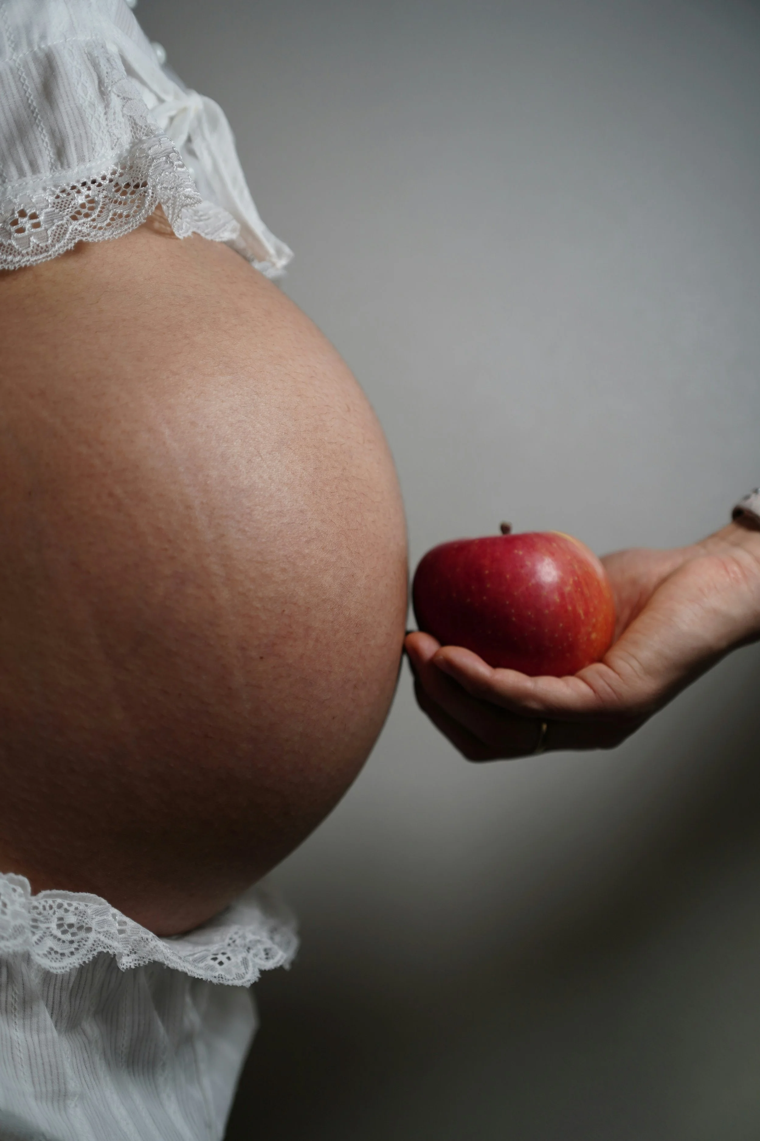 a photo of a pregnant woman’s belly and a small apple