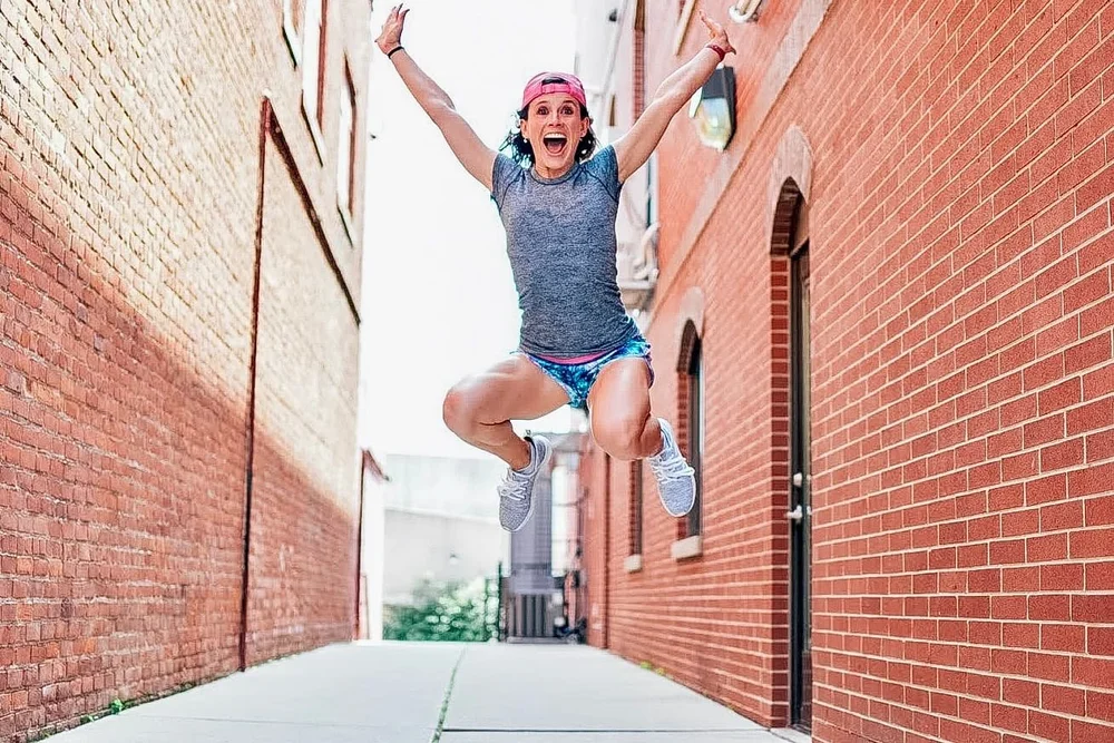 Nutrition coach Sarah Pelc Graca jumping in an alley