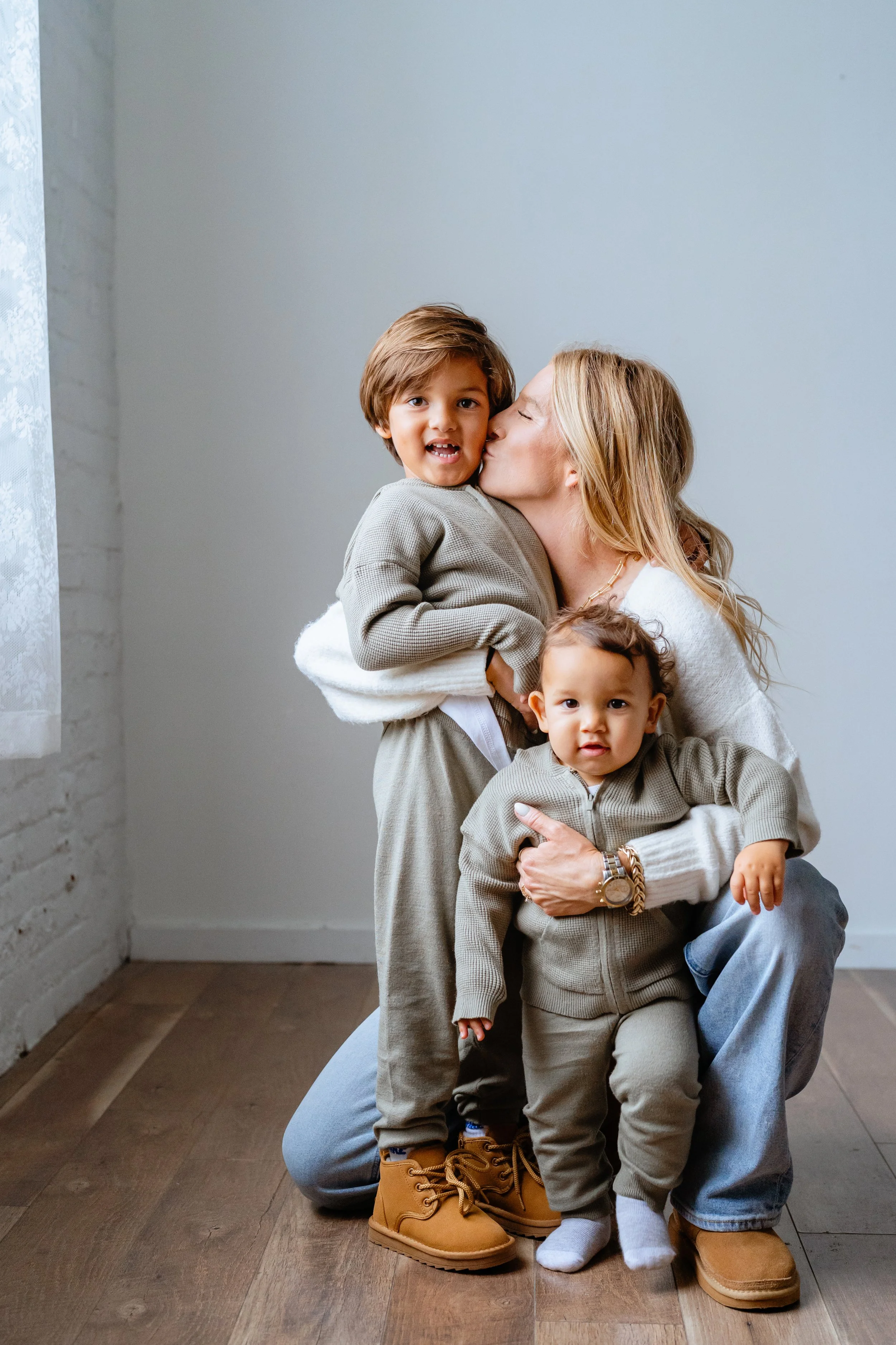 mom snuggles with young sons for professional family photos in tampa florida