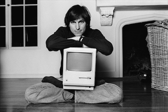Steve Jobs (1984) in classic lotus pose, cradling the first Mac.