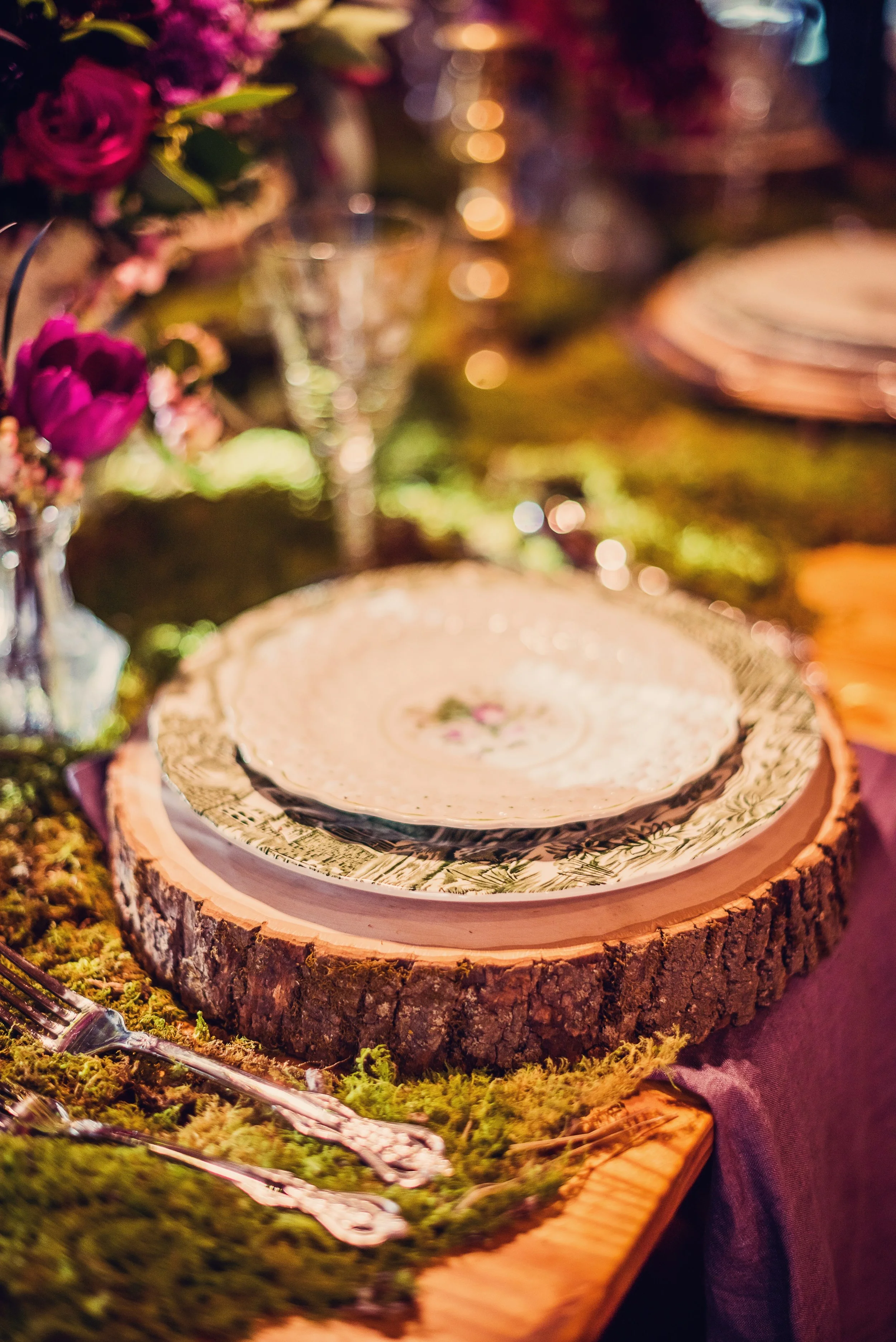 Montana enraptures you with year round beauty. As a result, designing in Montana is all about bringing the beautiful outdoors in. In the Fall, every tree comes alive with light and color casting a romantic display. We used natures palette and accentuated a deep aubergine for our floral display. We brought the majestic forest indoors using a table covering with sheet moss. Cut logs served as chargers for the plates. A mixture of antique dinnerware created an eclectic and rustic tone for this cozy fireside cabin dinner party in honor of the Bride and Groom!
