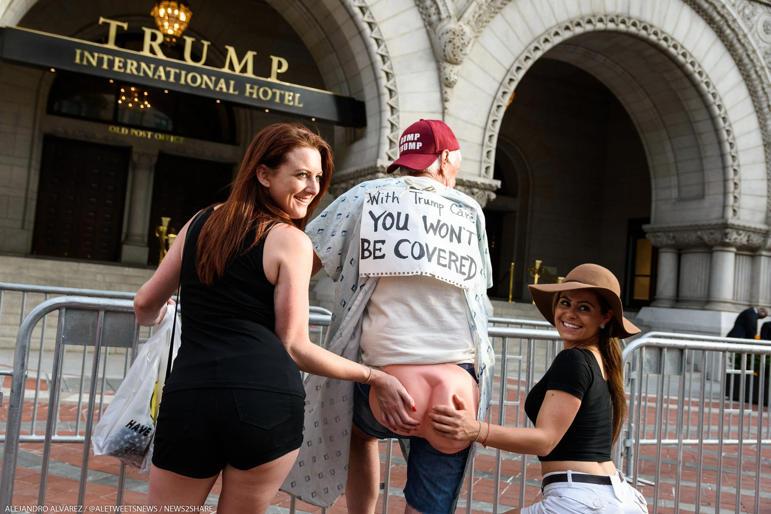 Two women pose for a photo with David Barrows, 69, dressed in a hospital gown and rubber buttocks.