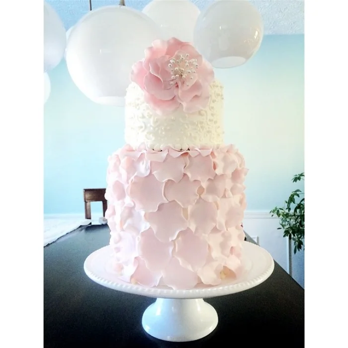  This baby shower cake is adorned with fondant petals and flower along with royal icing scroll work and sugar pearls