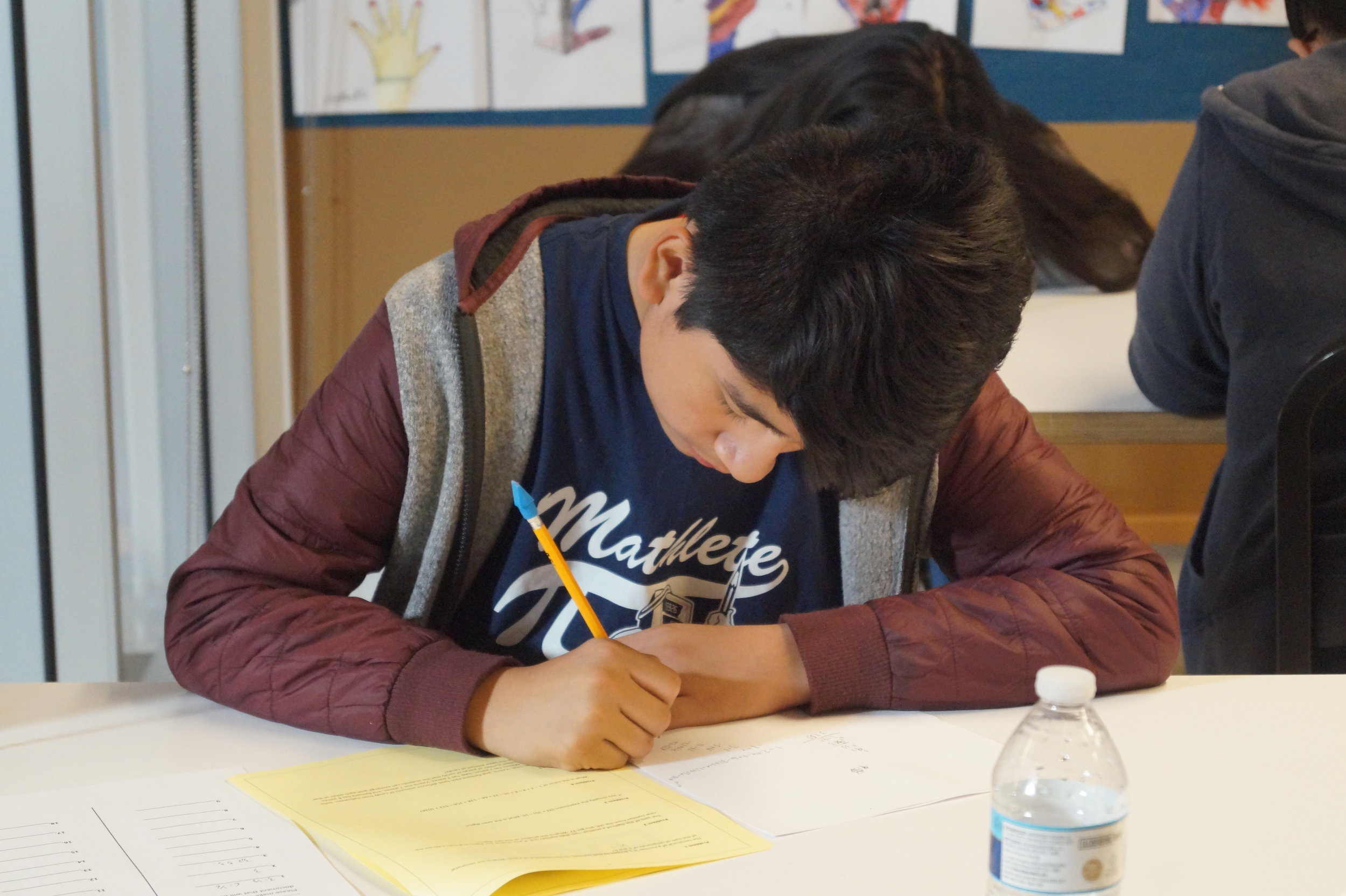  A student from Equitas Academy #2 dons his Mathletes shirt while working on the individual round questions.  