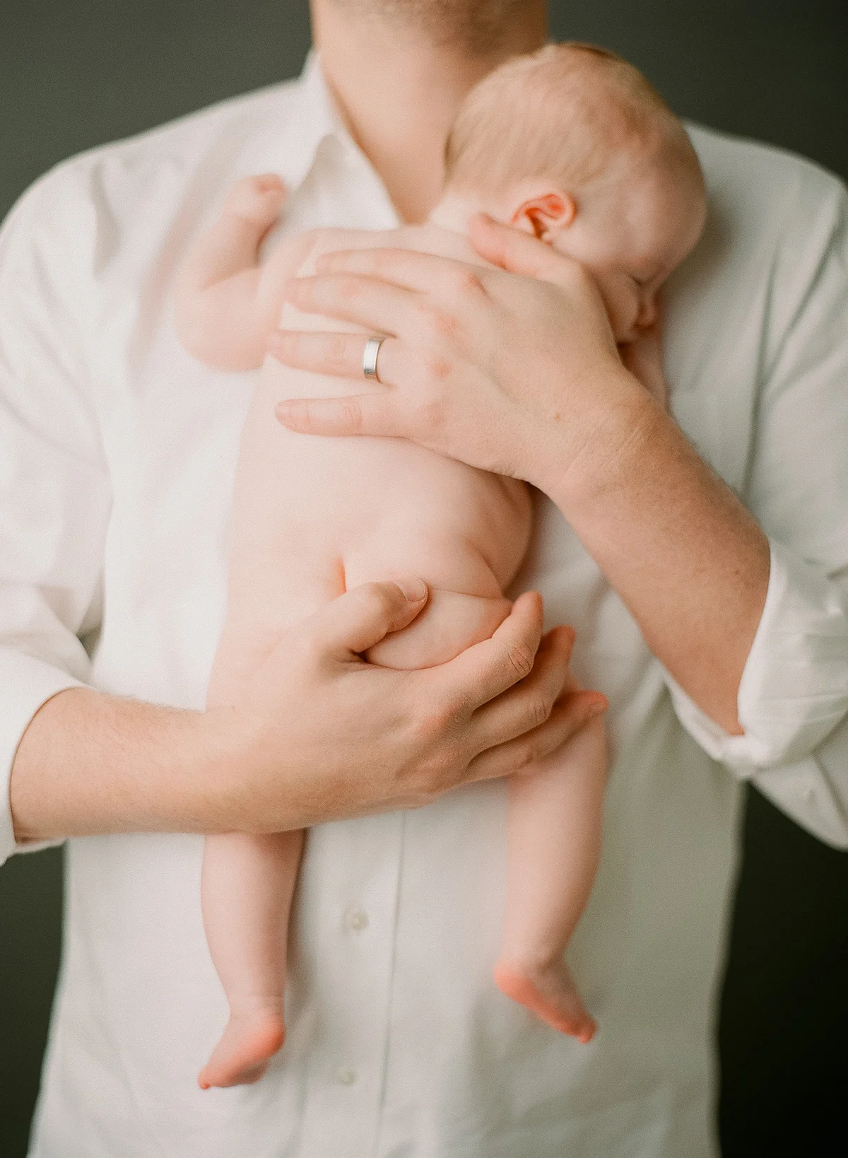 Newborn photography Seattle, by Sandra Coan. Studio photograph. Man holding sleeping baby.