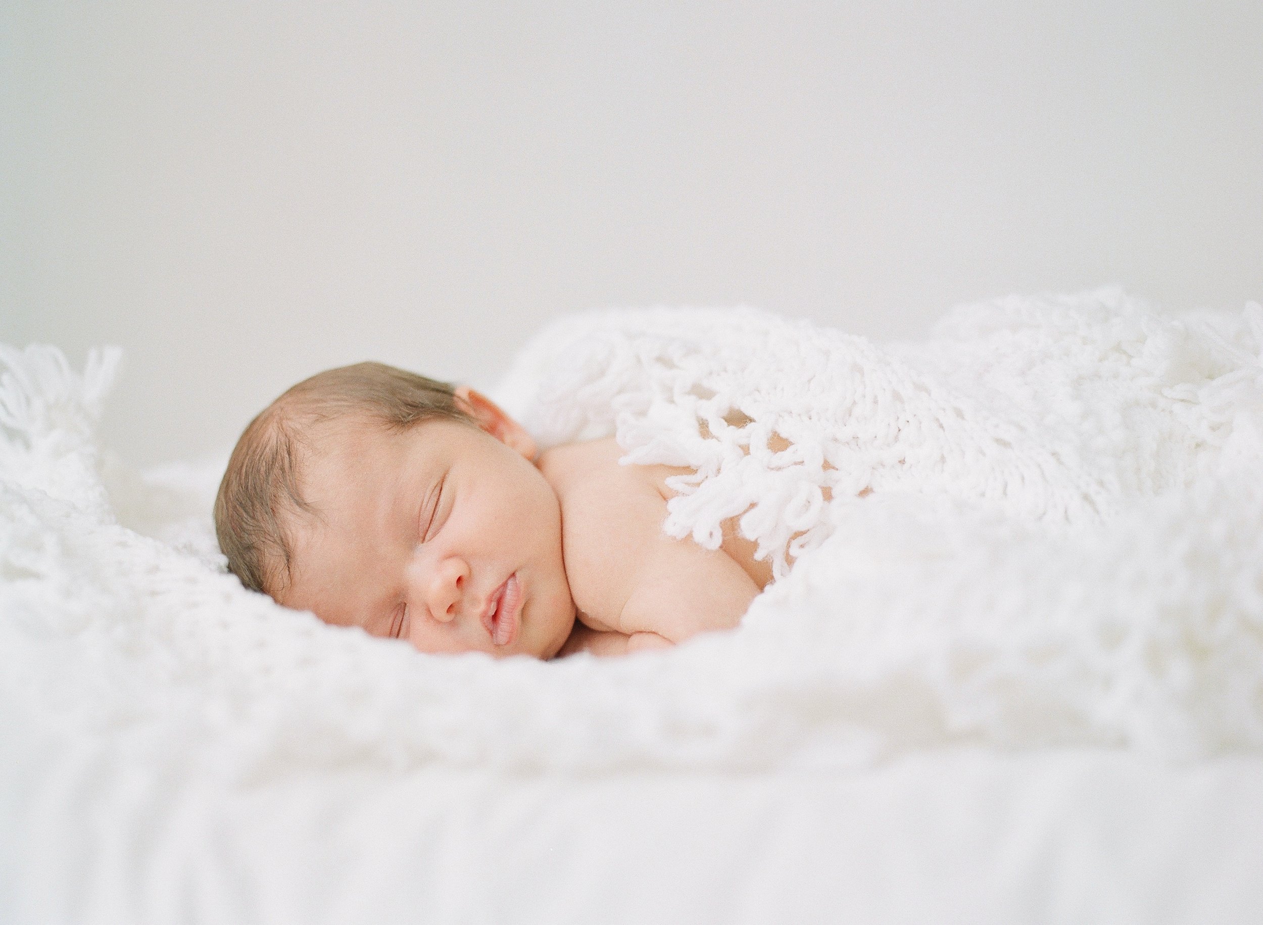 Sleeping newborn baby wrapped in a white blanket