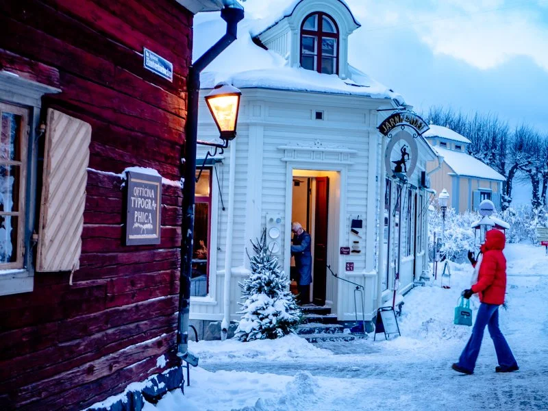 городской квартал Скансена в Стокгольме, красные традиционные домики, зимний вечер, темнеет, зажигают фонари.jpg