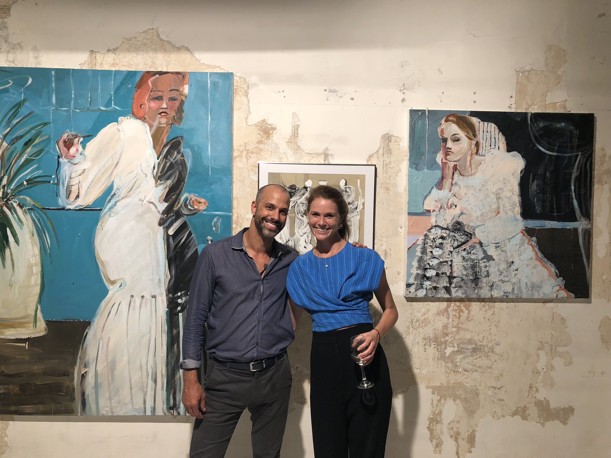 Mary Ball with Ozymandias Wines’ president and founder Rafe D’Amico, at “Organized Chaos,” an Ozymandias Wines fundraiser in 2018. Mary’s work is displayed on the wall behind them.
