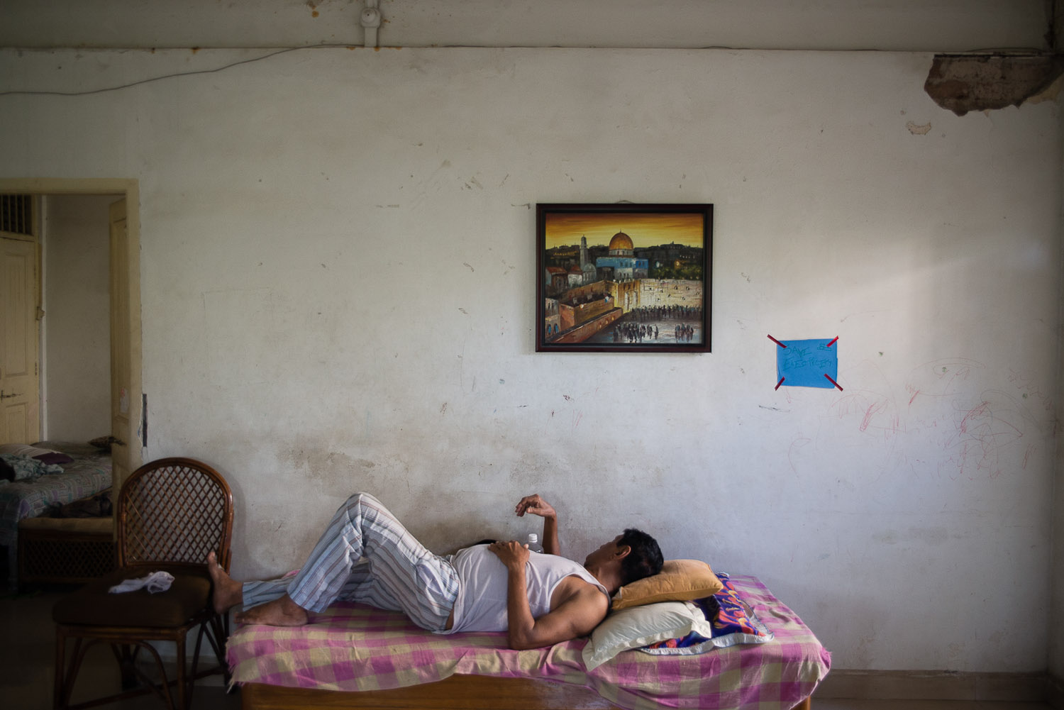  Benjamin Reuben Galsurkar takes a nap under a painting of Jerusalem in the hostel the Galsurkar family owns. The hostel was once a place to house refugees fleeing the Nazis during World War II, and then became a hostel to house Jewish students comin