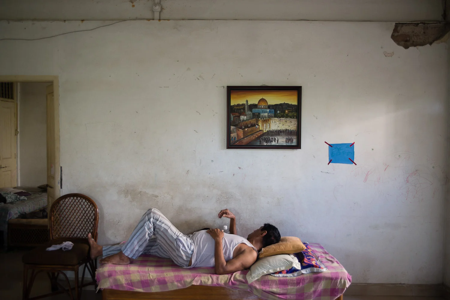 Benjamin Reuben Galsurkar takes a nap under a painting of Jerusalem in the hostel the Galsurkar family owns. The hostel was once a place to house refugees fleeing the Nazis during World War II, and then became a hostel to house Jewish students coming from outside Mumbai to study the religion.