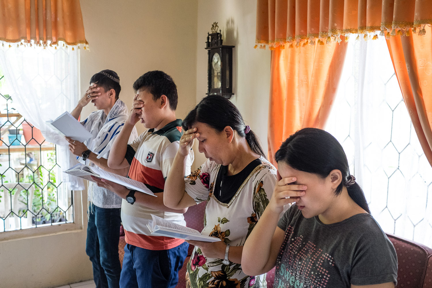 Vicky's third brother Otto Yonatan (Yishay Yonatan) (on left) and Ezra's visiting family recite the Shema during Saturday morning services at the Rambutuana home synagogue.