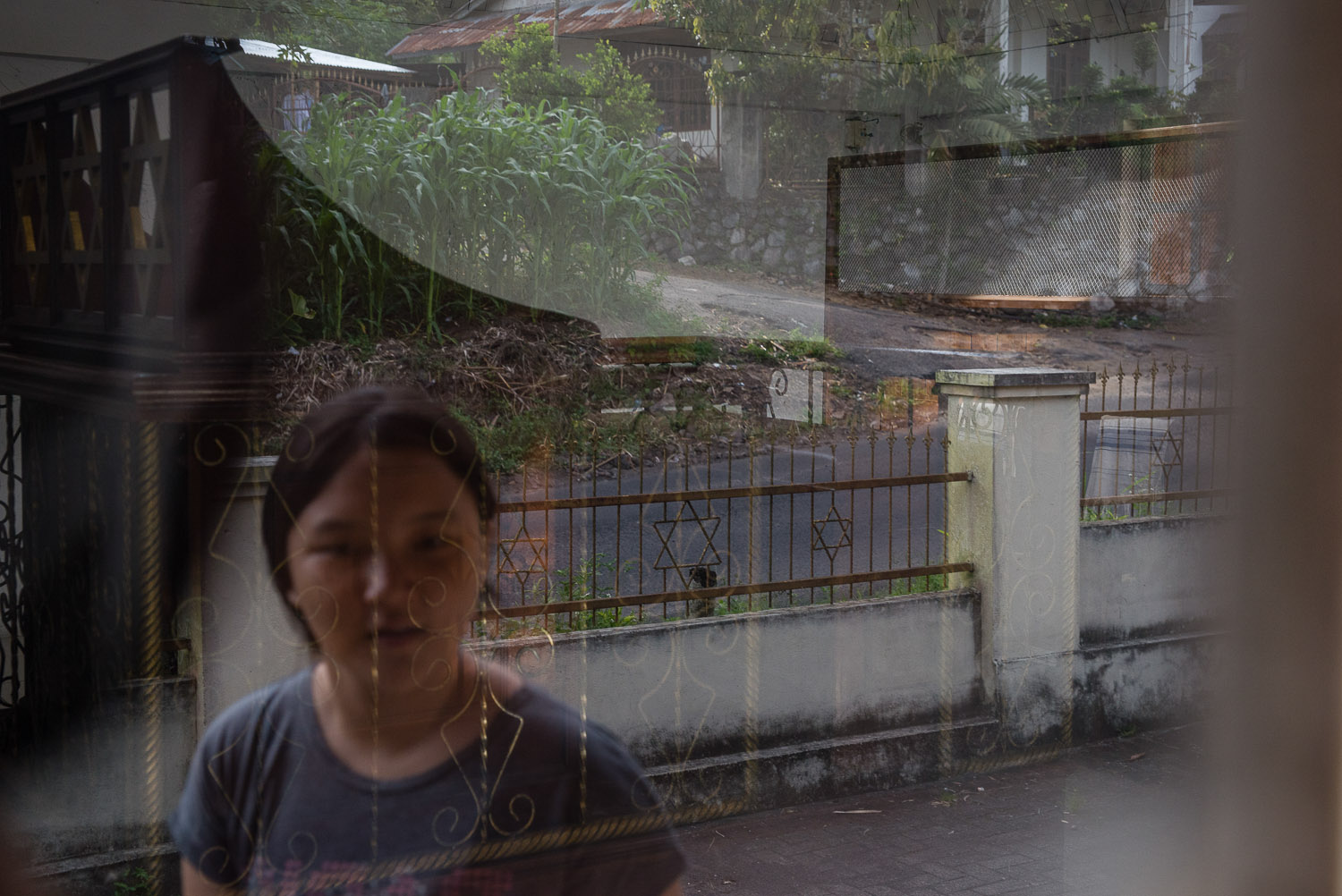   Ezra's daughter's face is reflected in the window of the locked synagogue in Manado. While Ezra's family came to pray at Vicky's home synagogue, Ezra is still somewhat affiliated with another group in Manado (with supposed links to the church) and 