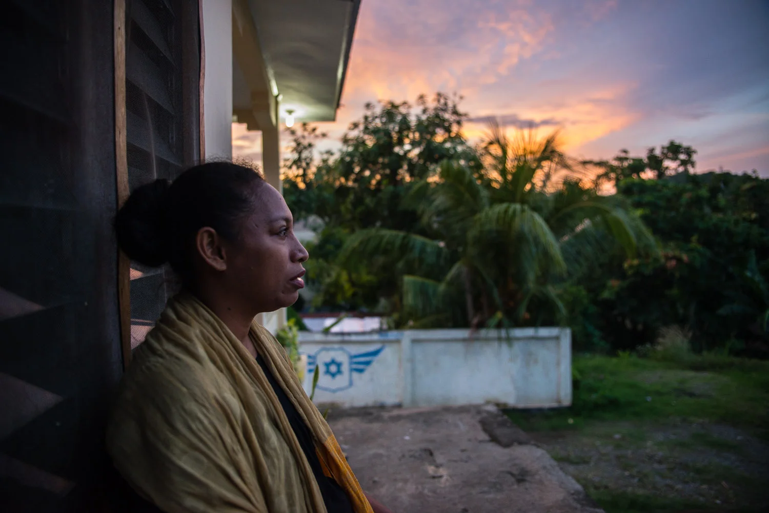 Diane Hokouoku sits outside her home which also serves as the main synagogue for the Jewish community in Jayapura, West Papua, Indonesia. She visited Israel once and remembers "I tried to get up every day to see the sunshine. I wanted to know what it looked like in Israel. It was beautiful, so many colors. We live in the Far East, here, but in Israel is in the middle. I would look east and see, far away, there is Jayapura."
