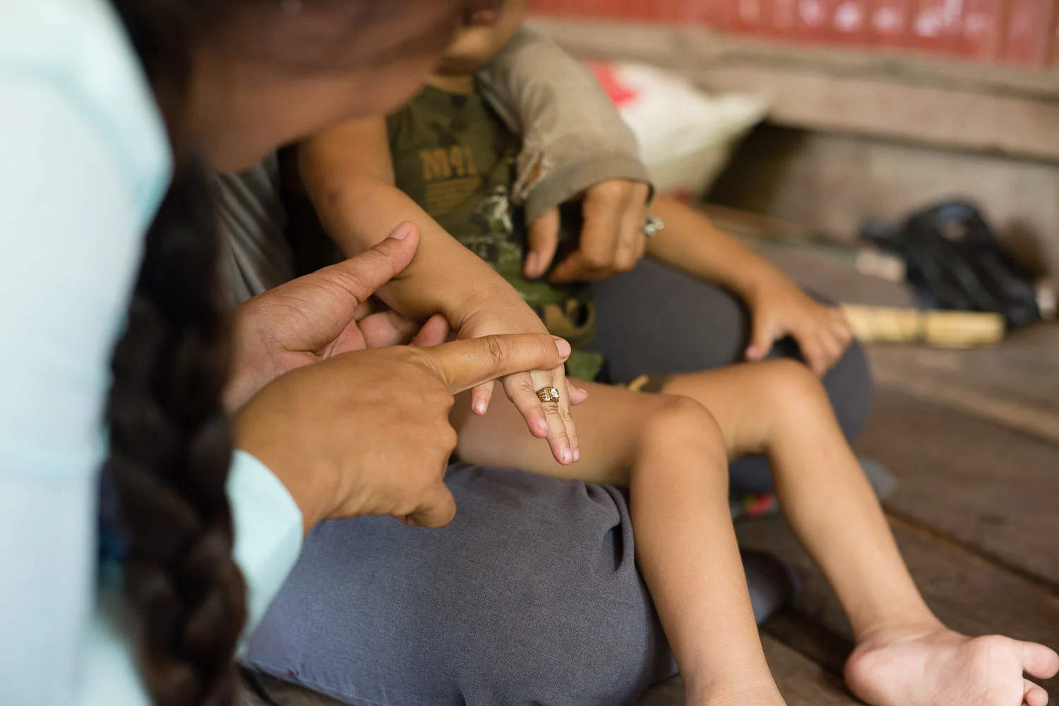 Phearom helps to straighten out Lihour's fingers, as they cramp up tightly often due to his cerebral palsy. 