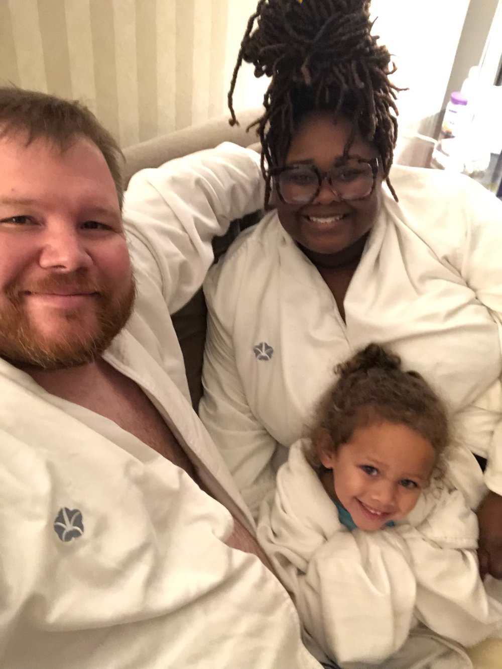 A family poses in hotel robes for a picture.