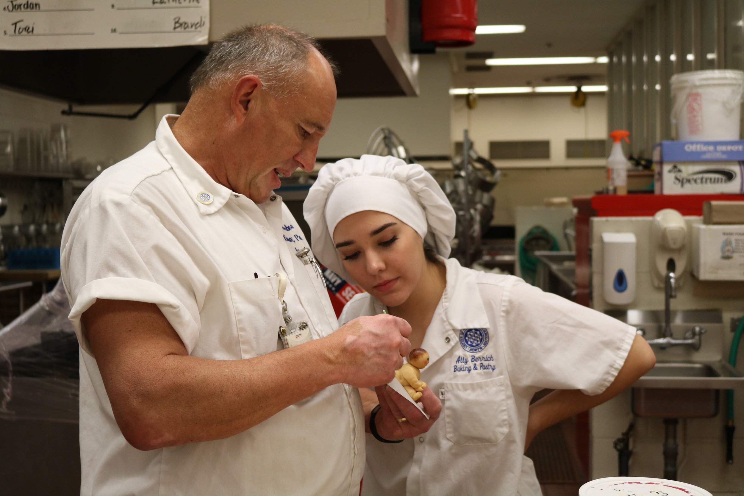  Peter Akerboom, left, a baking and pastry instructor, teaches Ally Berrich a technique for using marzipan in a course at the Center of Applied Technology North in Severn, Md., on May 11, 2016.  