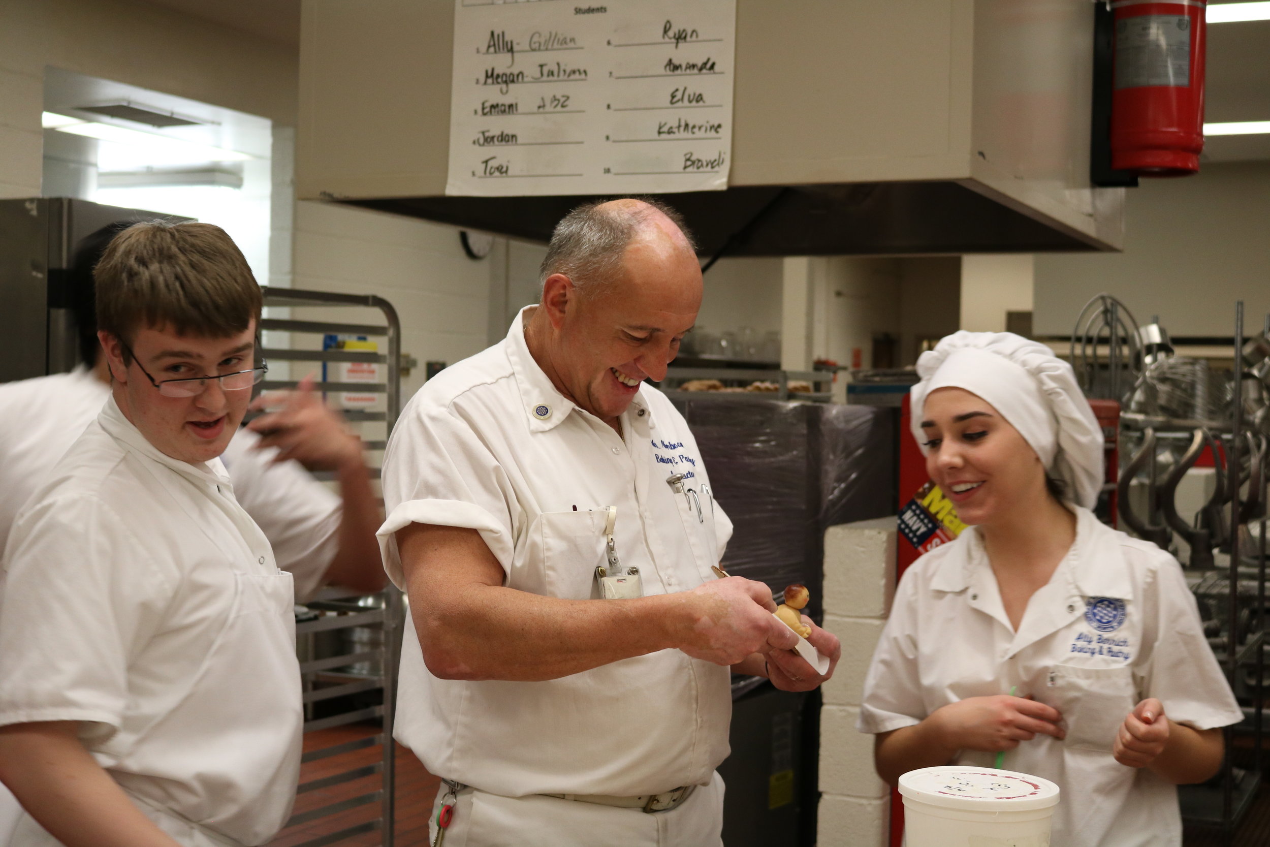   Peter Akerboom, center, makes a marzipan joke with Ally Berrich in a baking and pastry course at the Center of Applied Technology North in Severn, Md., on May 11, 2016  