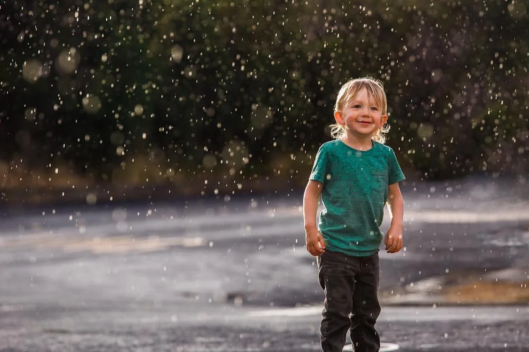 A beautiful summer rain started falling during sunset, and I had mere seconds to race in to the house, get my camera (which is almost always on my desk in the living room with lens attached) and capture this. It is one of my favorite images ever taken of my son. 