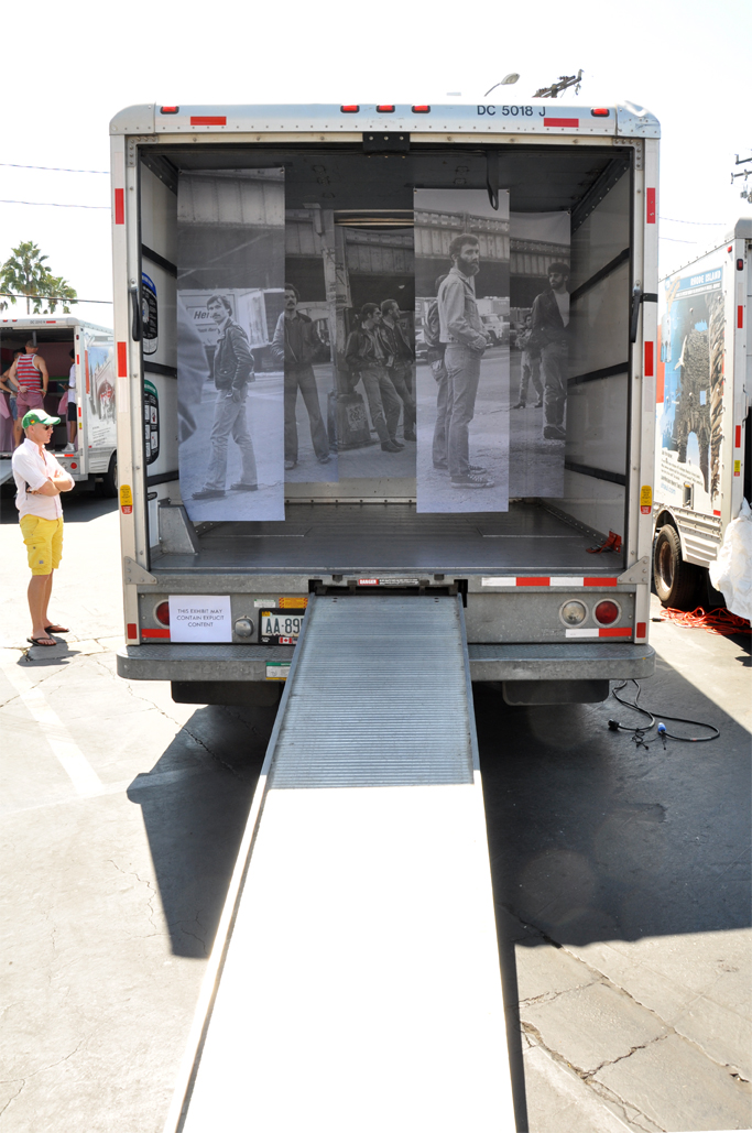    Exterior view of the installation. A viewer reads and essay by the artist,&nbsp;installed on the side of the truck, documenting the performative aspect of the piece's creation.&nbsp;   